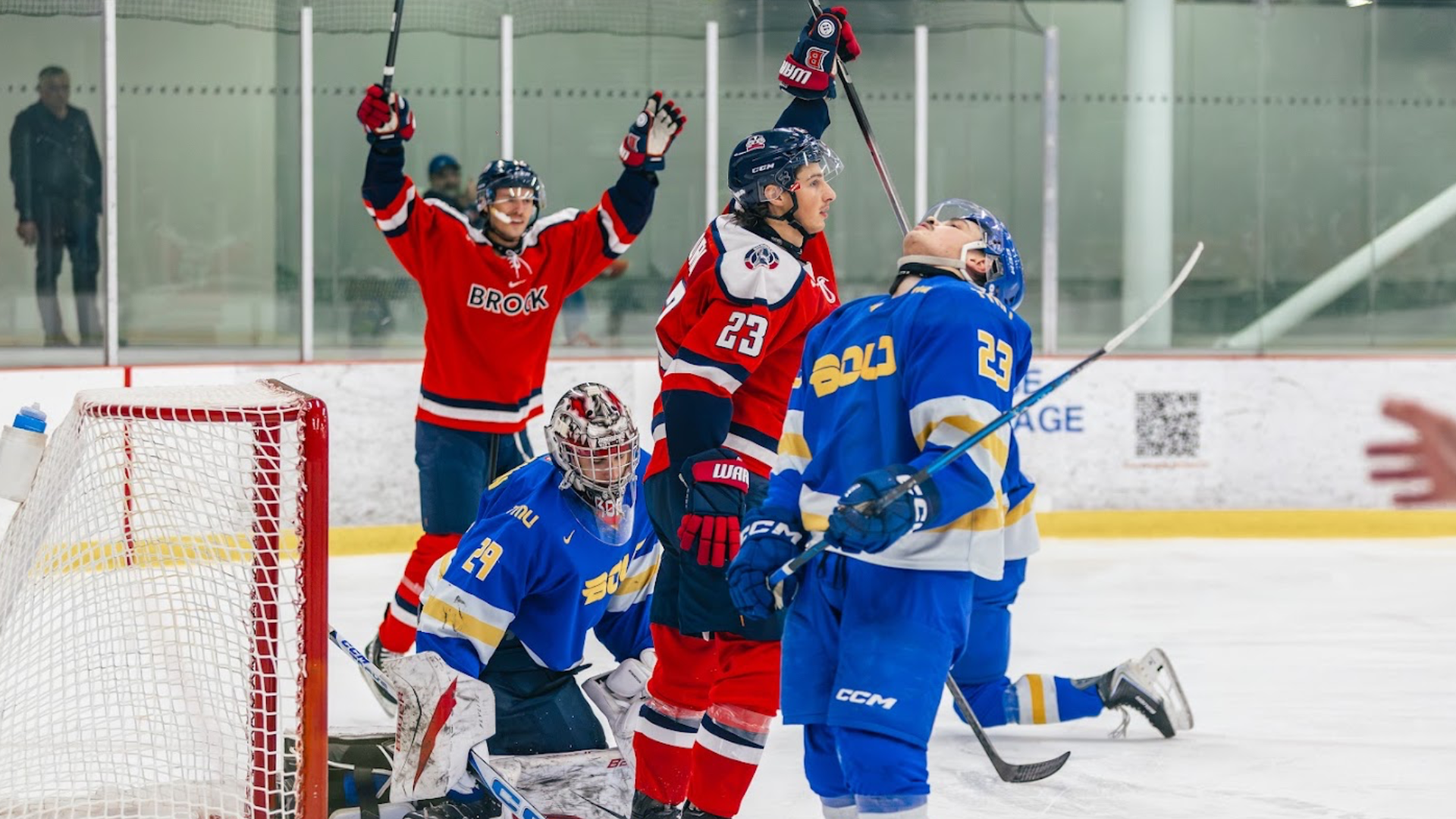 A Brock men's hockey player points to the air in celebration