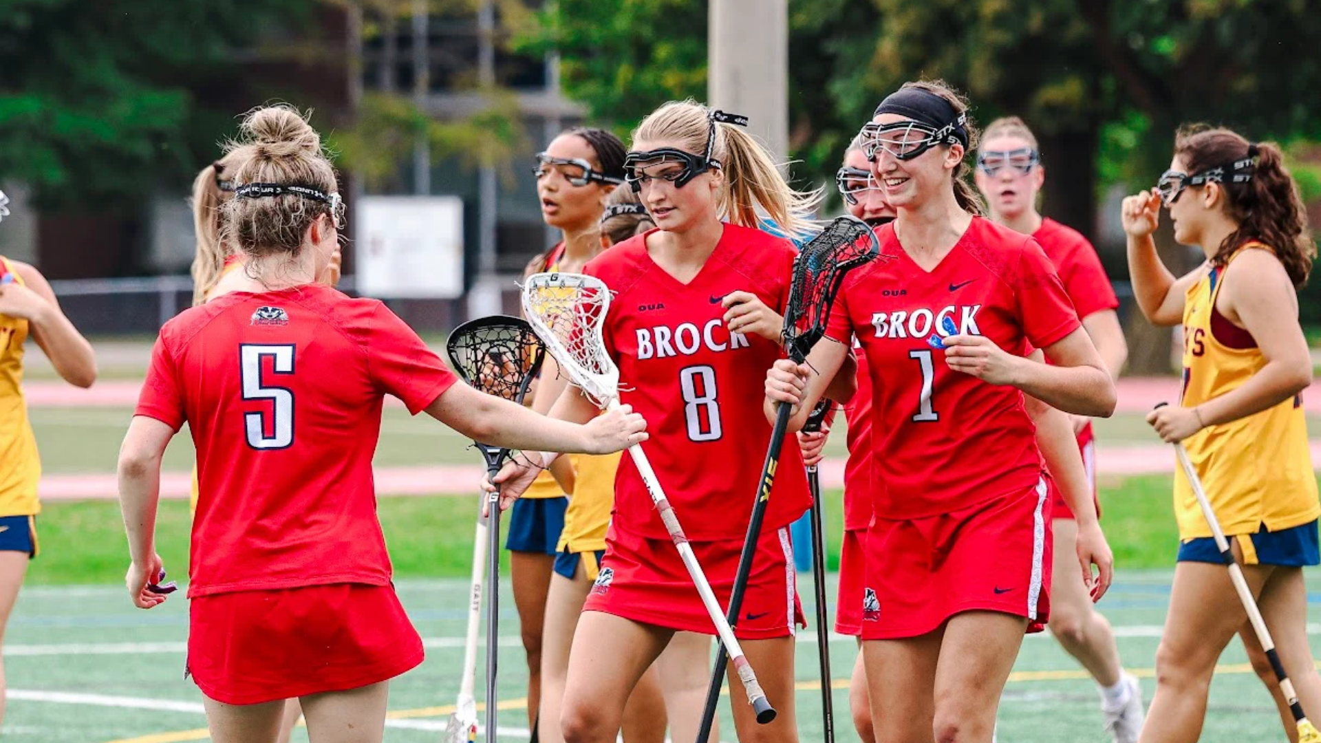 Three Brock women's lacrosse players celebrate a goal