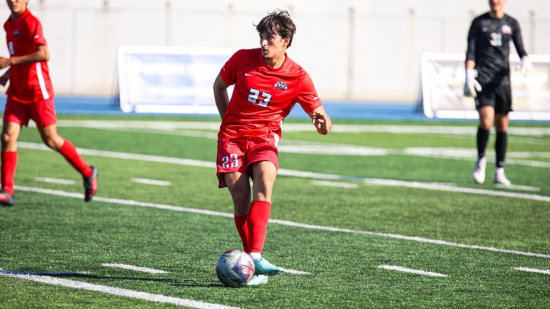 A Brock men's soccer player passes the ball forward