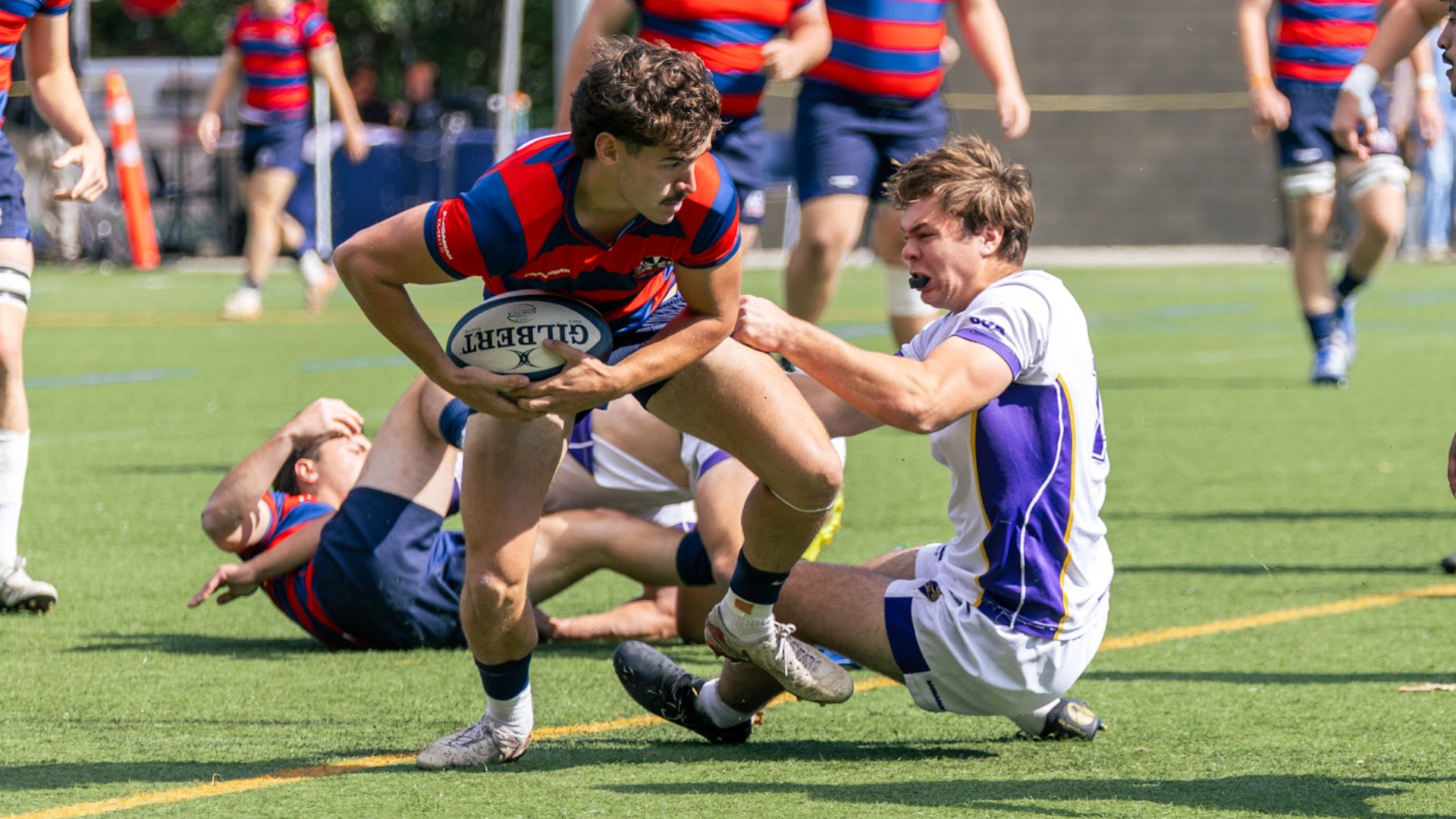 A Brock men's rugby player fights to break a tackle