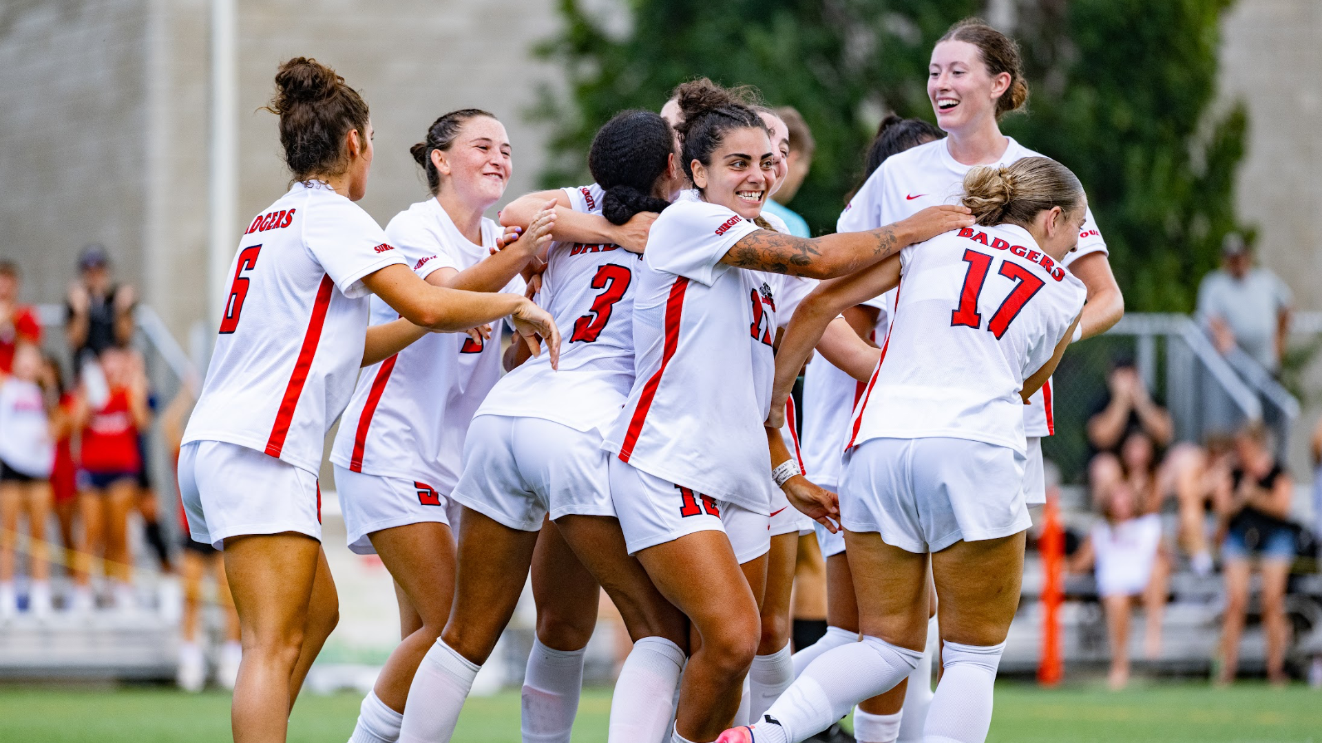 A group of Brock Badgers women's soccer team players huddle to celebrate a gaol