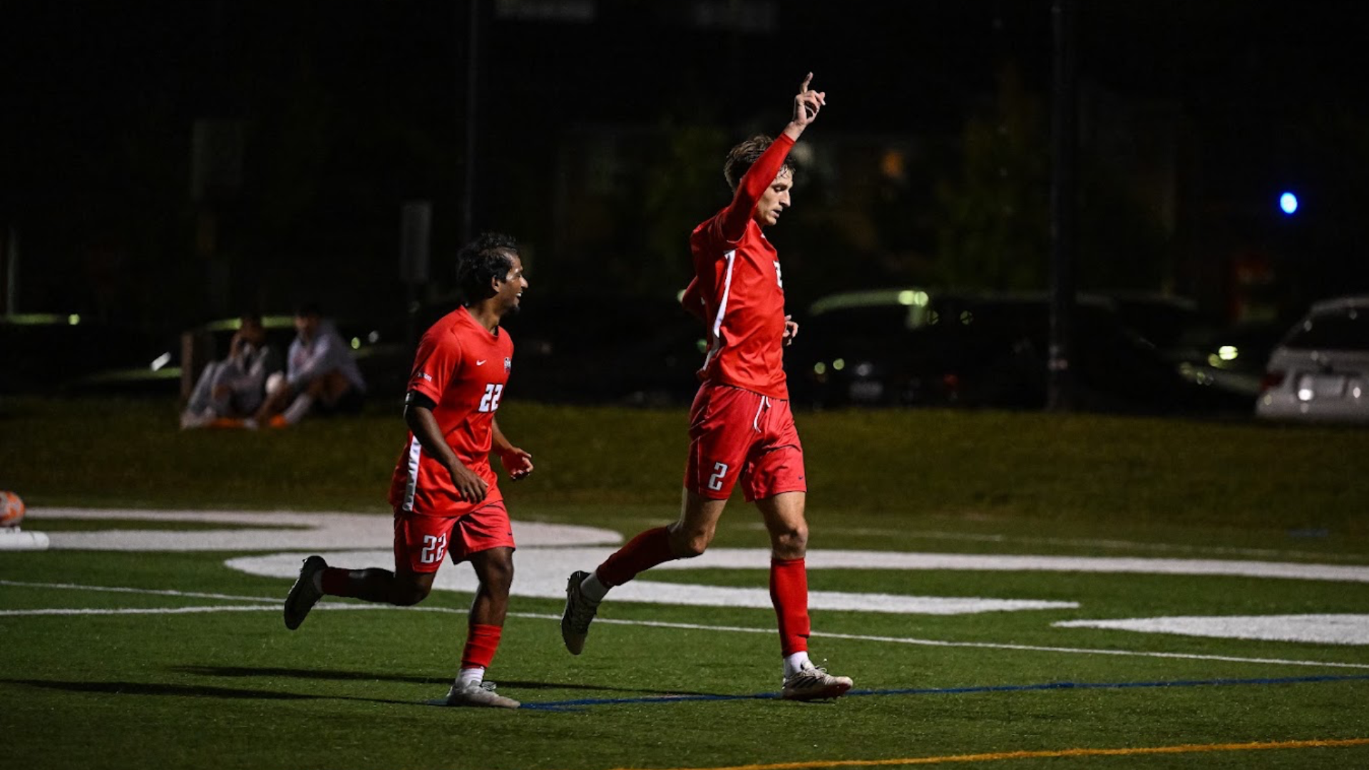 A Brock men's soccer player point up to the air