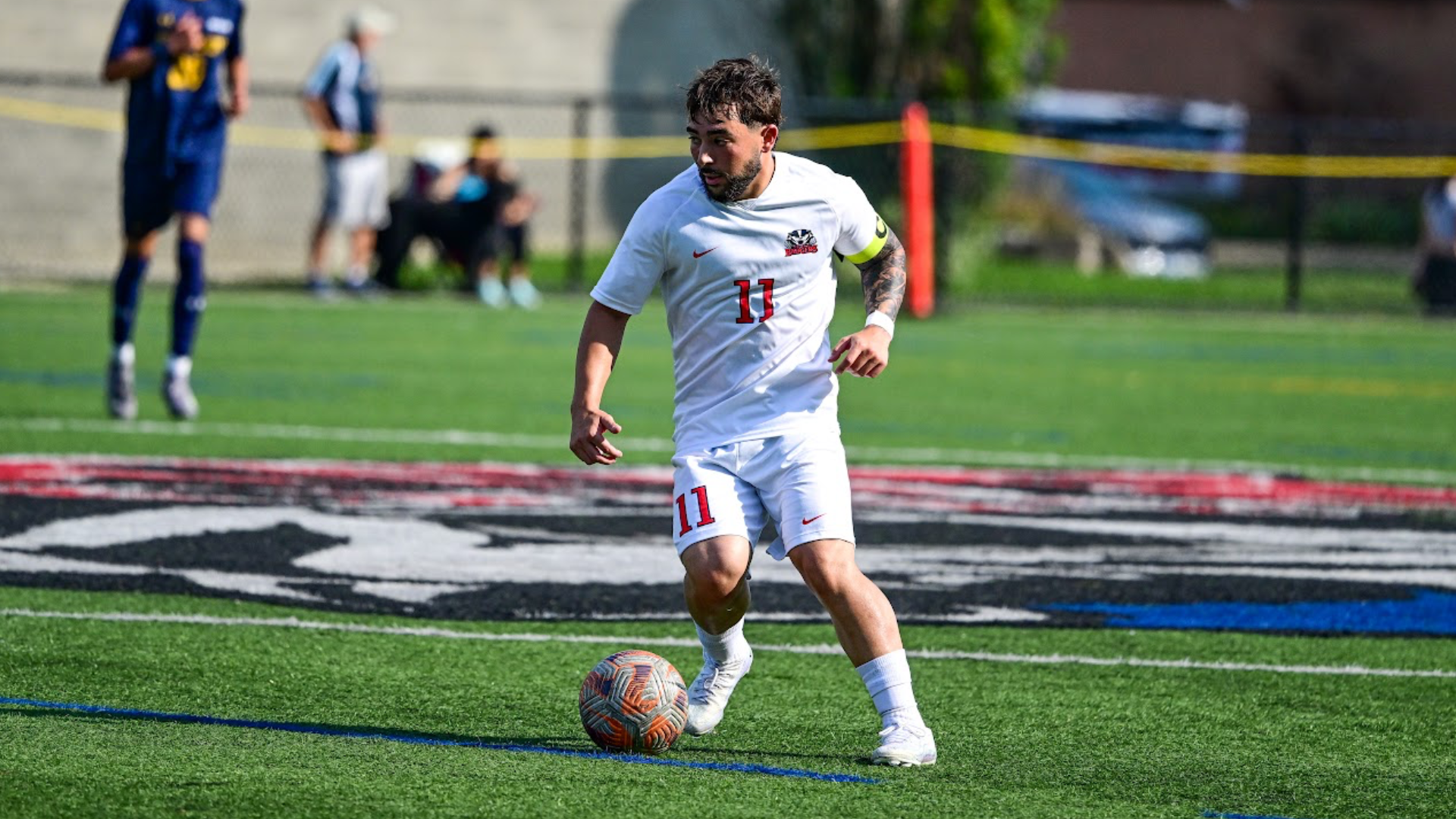 A Brock men's soccer player carries the ball forward