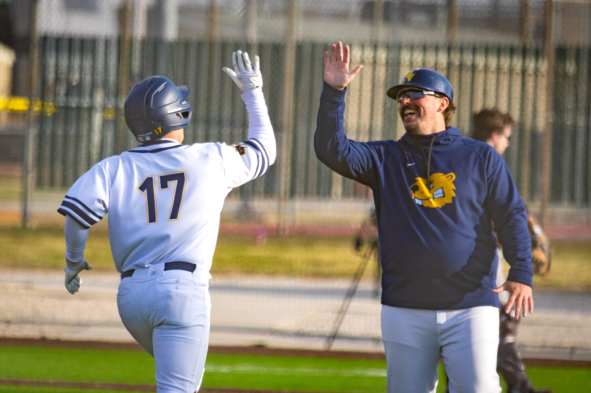 Teagen Kasel high fives coach Nate Hanner, BVU baseball vs. Augsburg