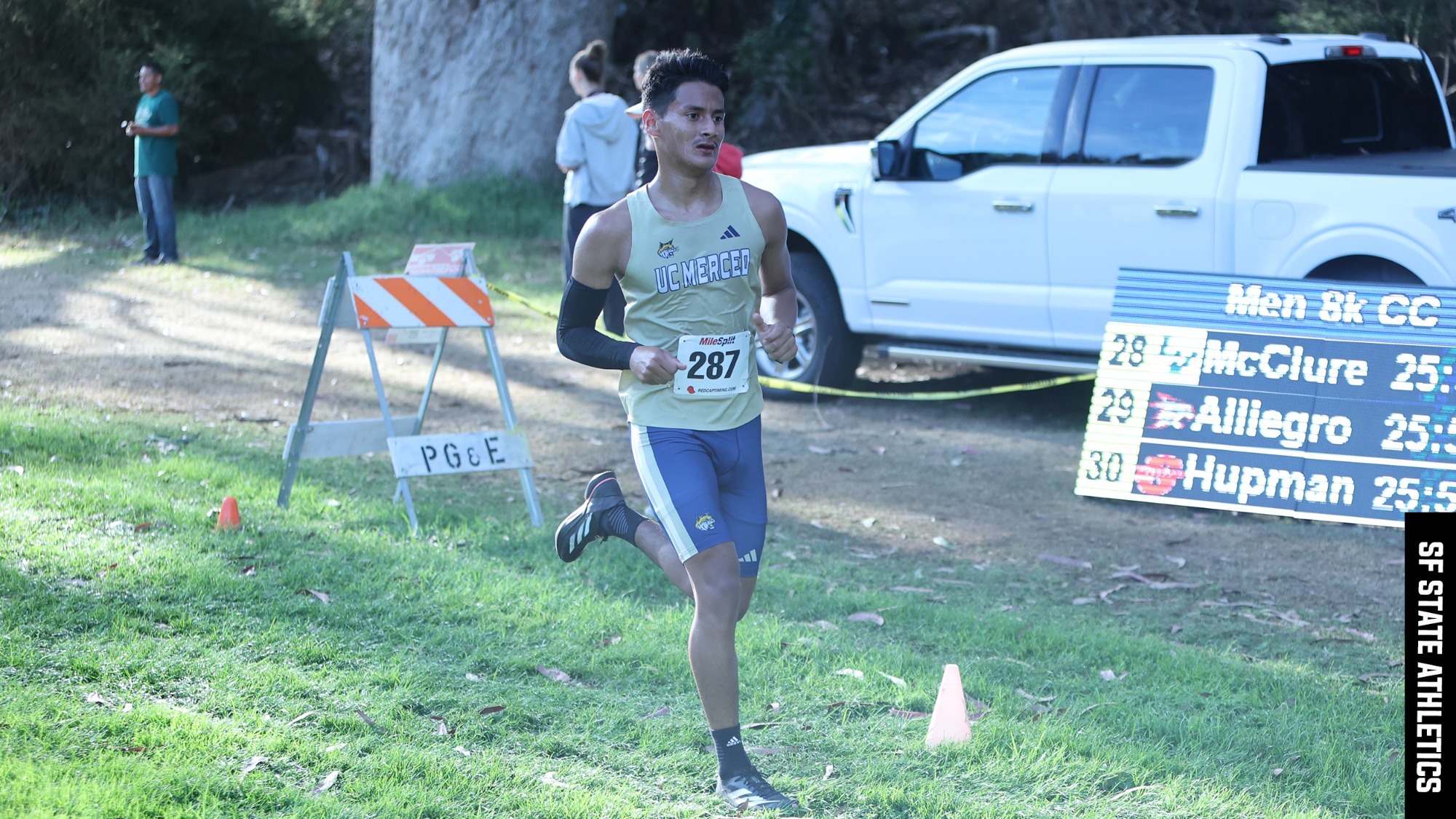 Alberto Guevara running a race with the scoreboard and fans in the background.
