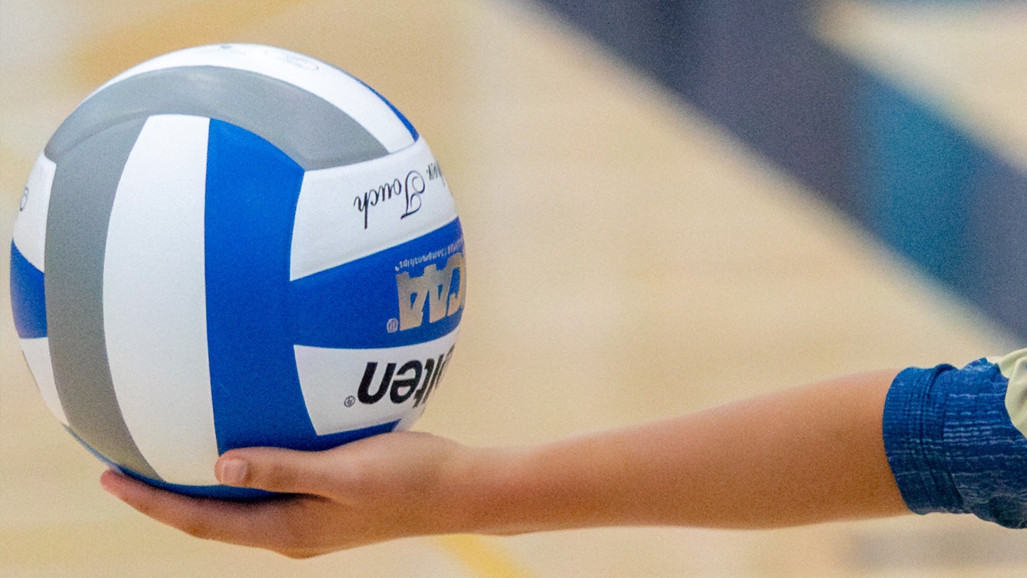 Women's volleyball player holding a blue and white volleyball