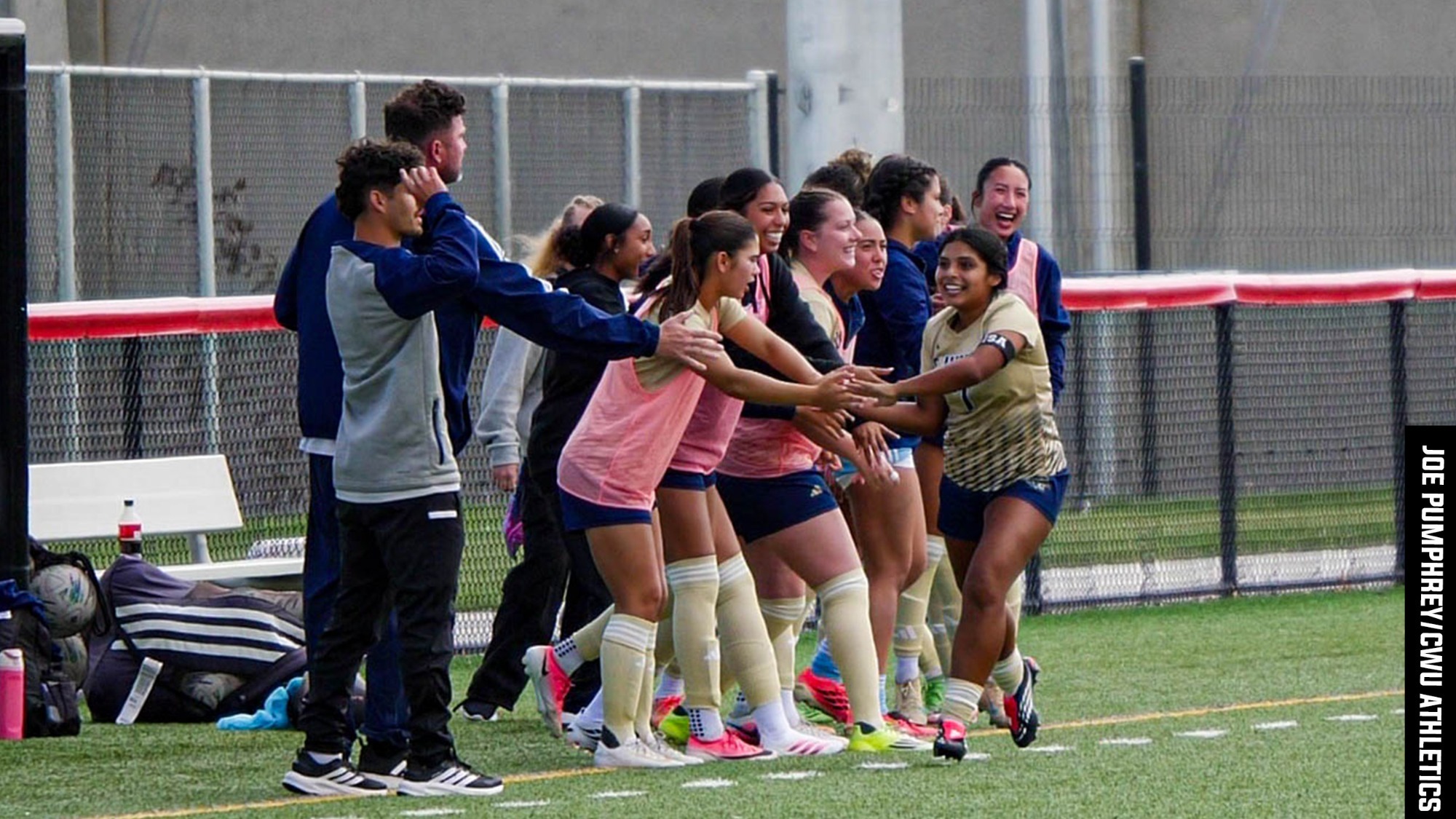 Alexia Alva celebrating a goal and running down the sideline high-fiving her teammates at Central Washington