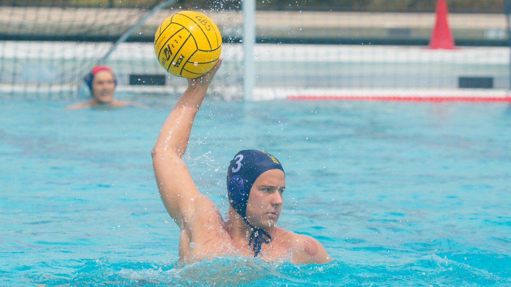 Andrew Jones Shooting the water polo ball at the UC Merced Aquatics Center. Goalkeeper Matthew Lloyd is in the background.