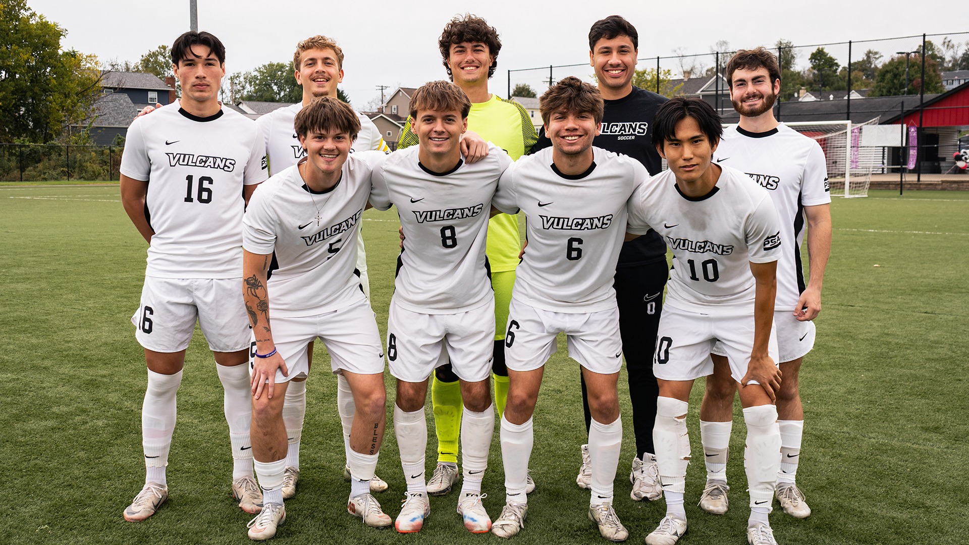 Nine members of the California men's soccer team pose together on the field in uniform.