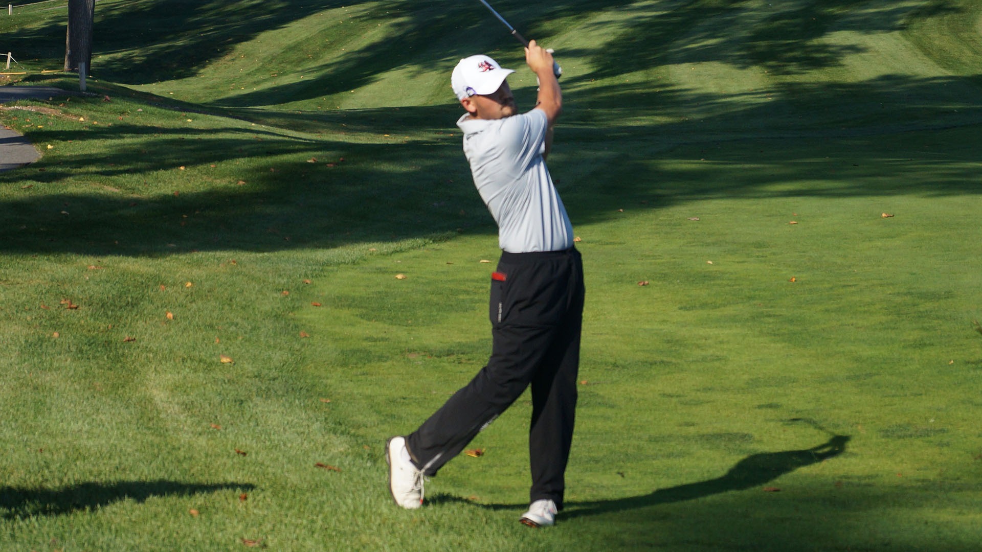 California golfer Nixen Erdely follows through on a golf swing on a sunny green course
