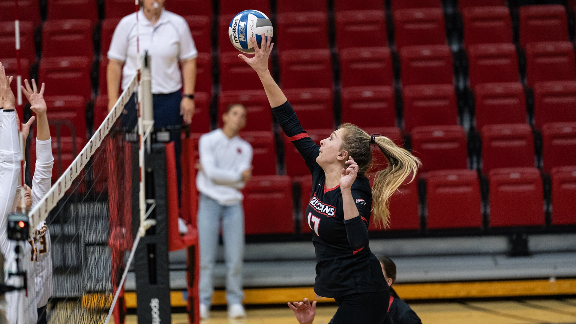 California volleyball player Lindsey Scammell (No. 17) reaches high to tip the ball over the net during a match.