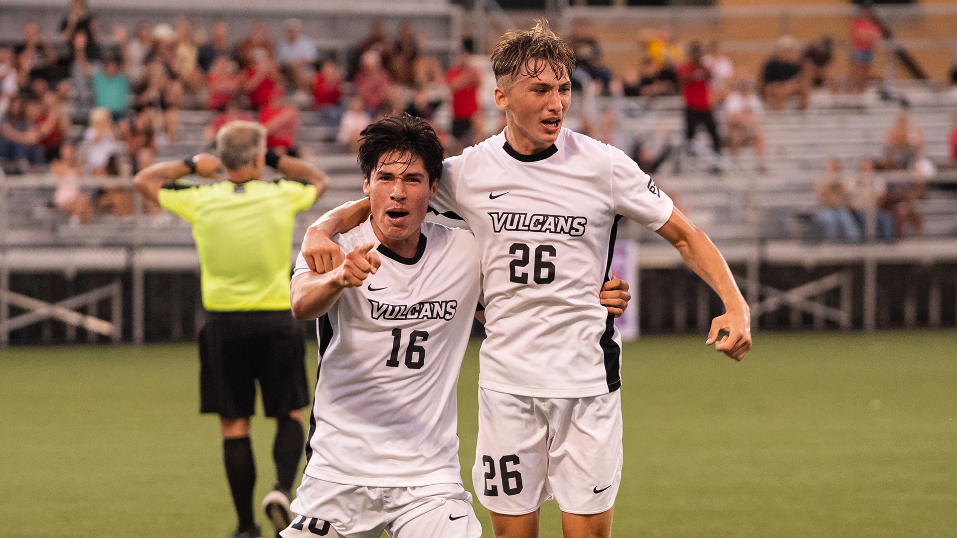 Jaime Marcelo Espinosa (#16) points forward and puts an arm around teammate Ryan Maloney (#26) while celebrating his game-winning goal for the Vulcans soccer team.
