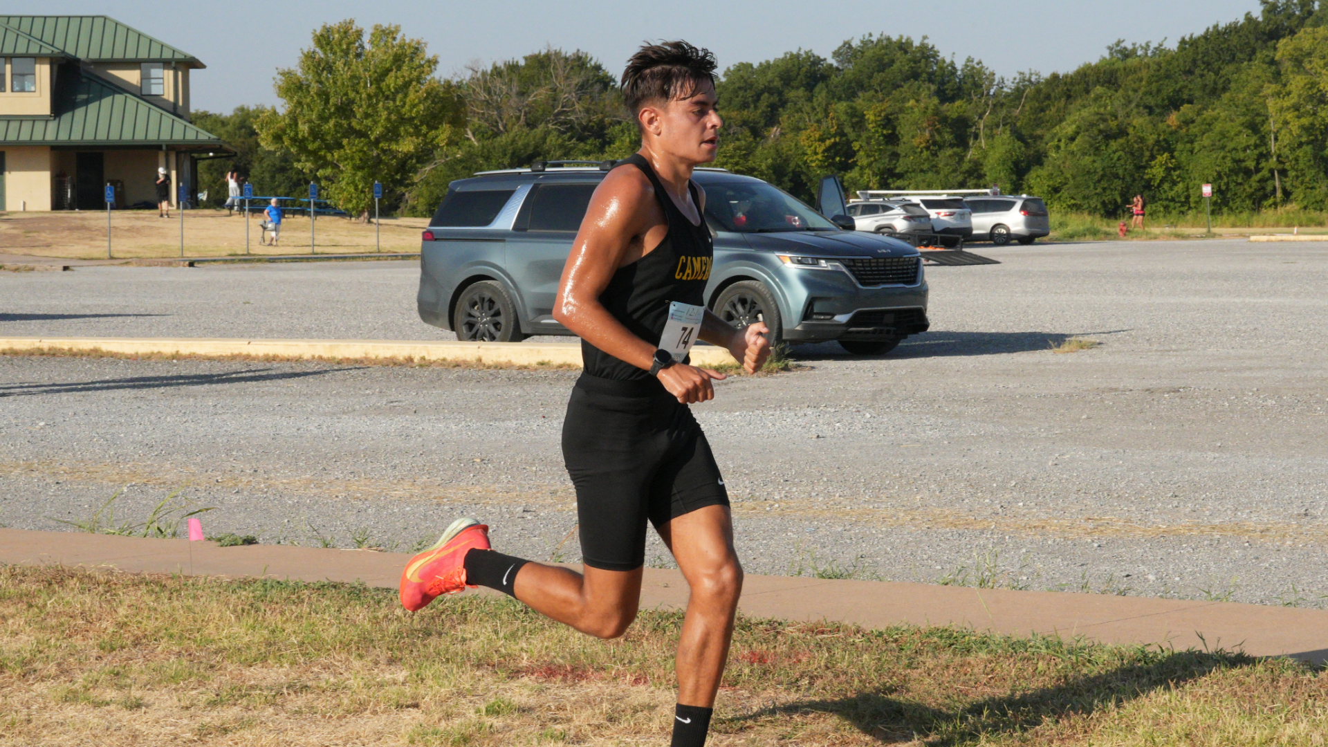 A Cameron University men's cross country runner competes outdoors in a black and gold uniform
