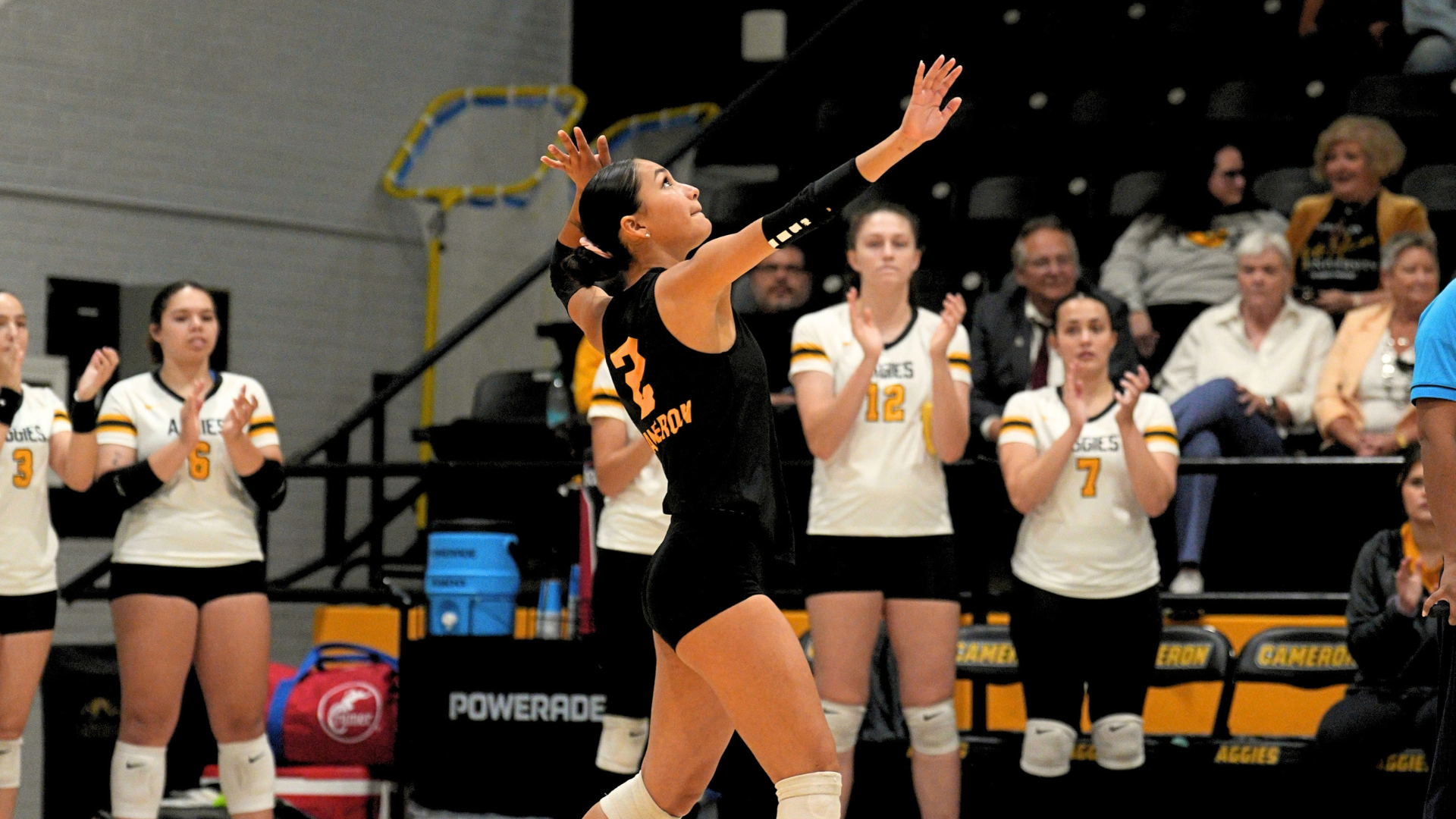 Cameron Volleyball player goes to serve as teammates watch. 