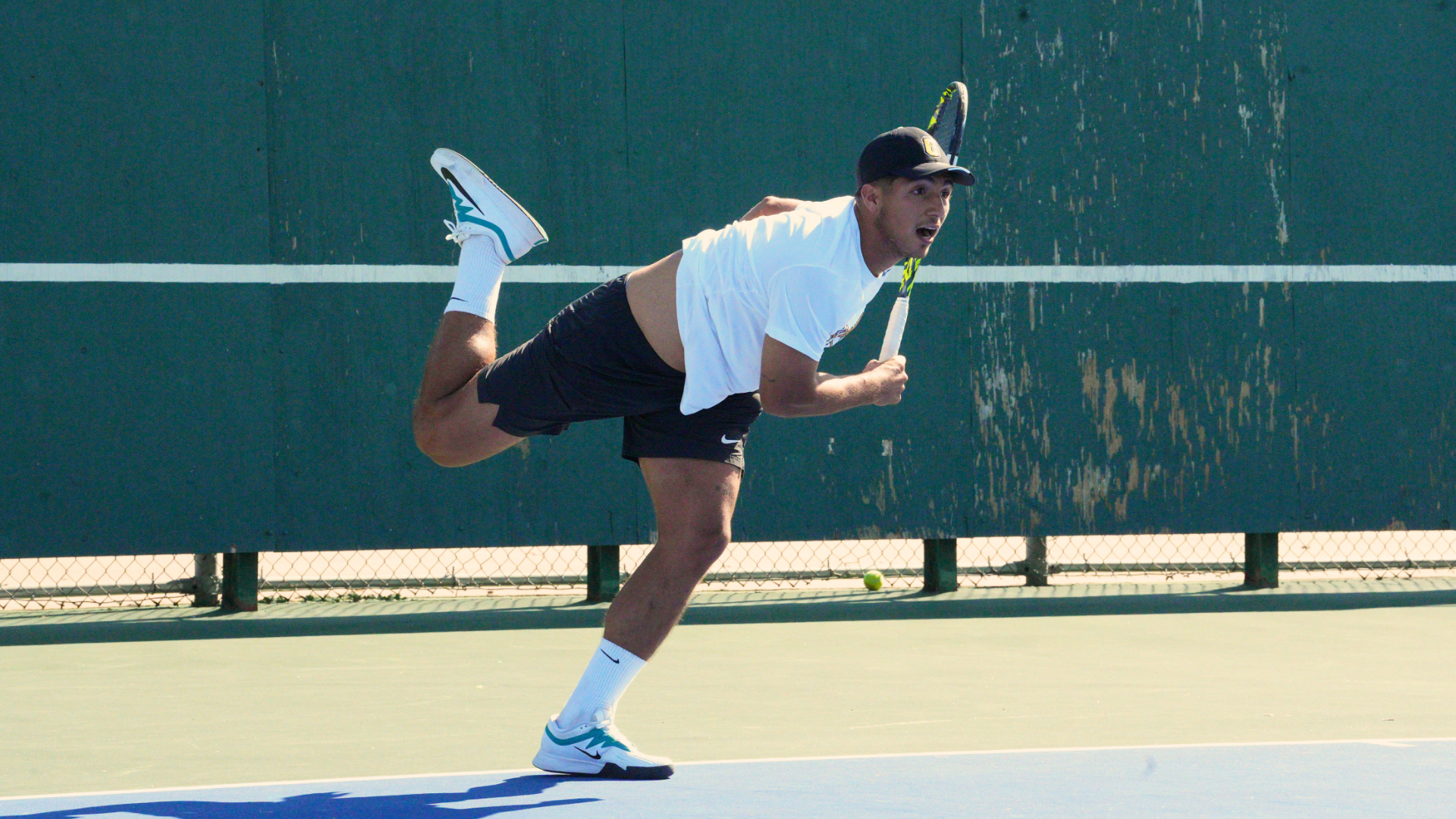 Cameron men's tennis player in the follow through of his serve