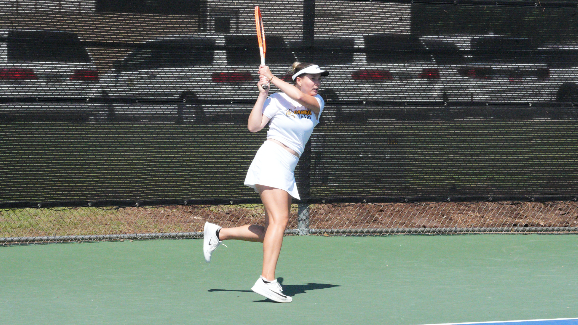 Cameron women's tennis player wearing white hitting a backhand