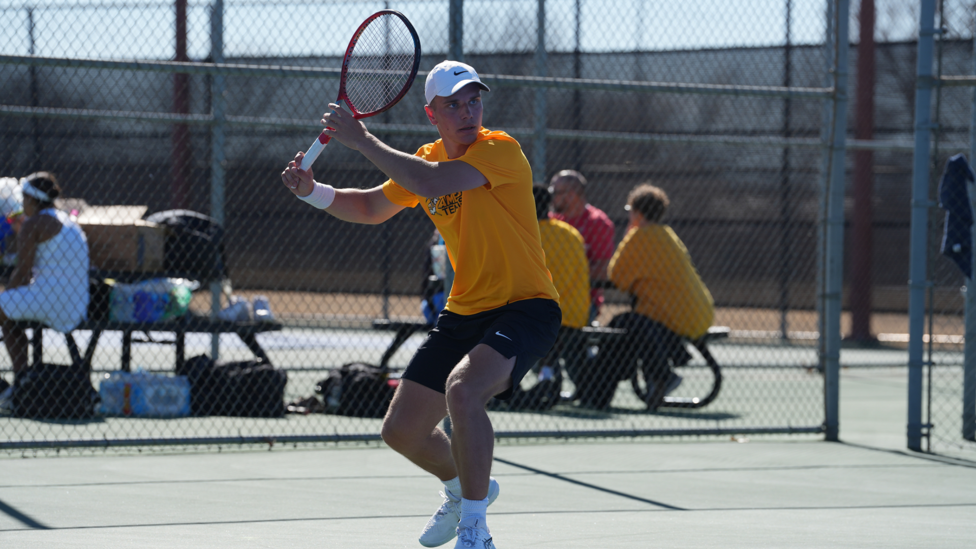 Cameron men's tennis player wearing yellow and white preparing to hit a forehand