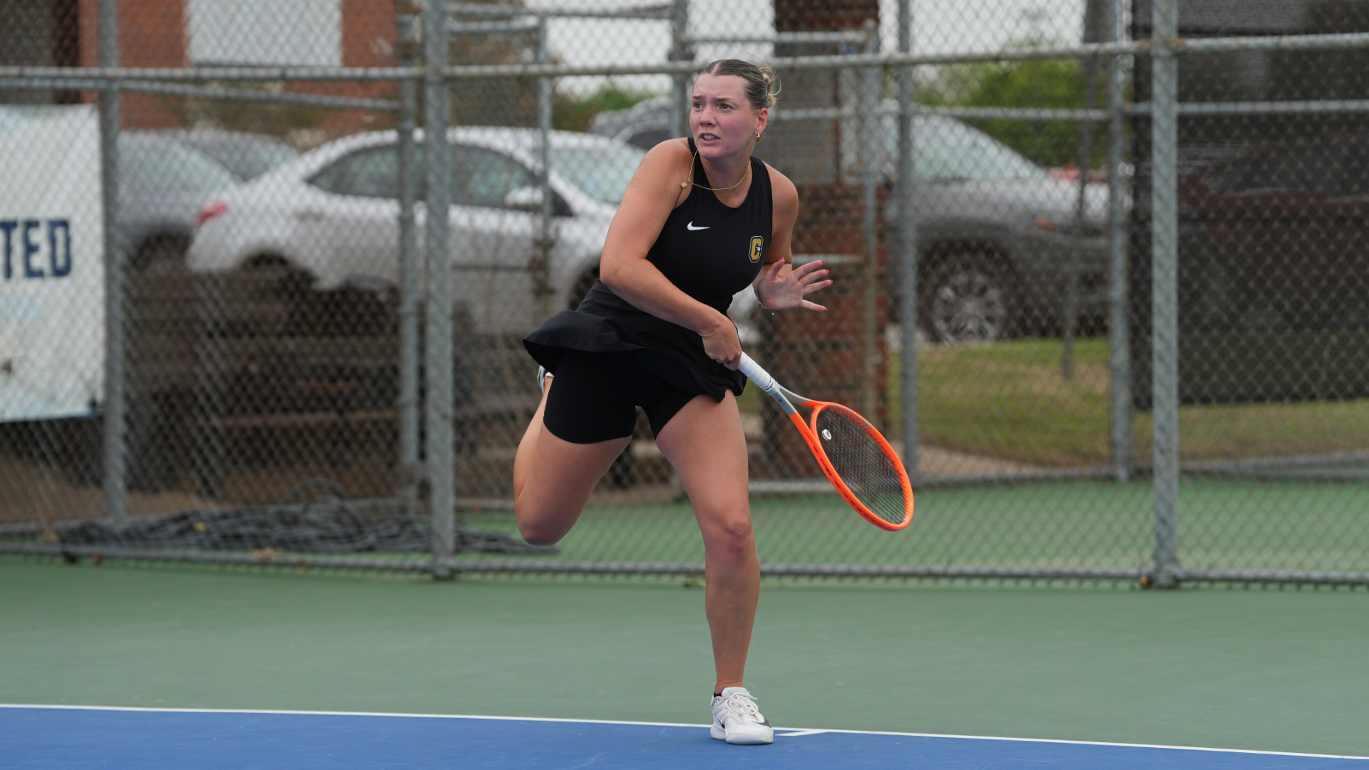 Cameron women's tennis player wearing black following through on a forehand