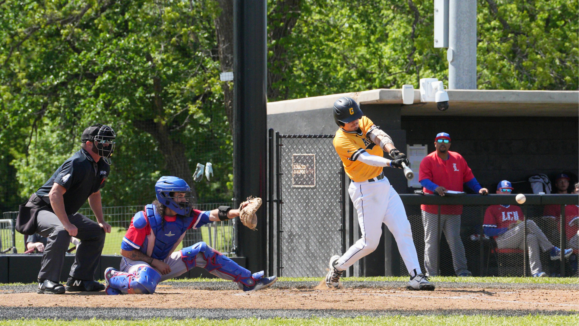 baseball player will bradley hits ball in front of umpire and lubbock christian catcher