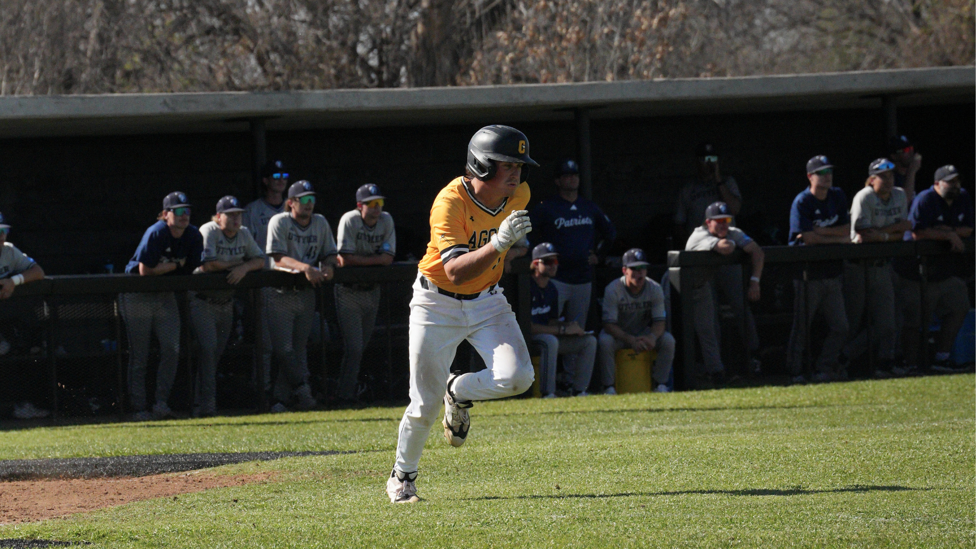 Baseball Player Hunter Tate runs down the baseline as the opposing team looks on.