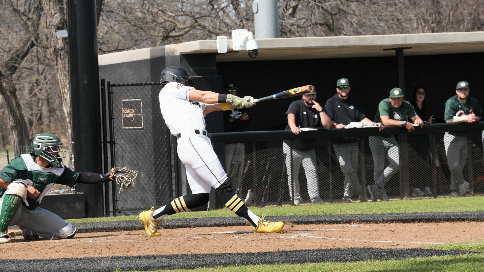 Baseball Player Diego Villarreal swings bat at contest while opposing team and catcher look on.