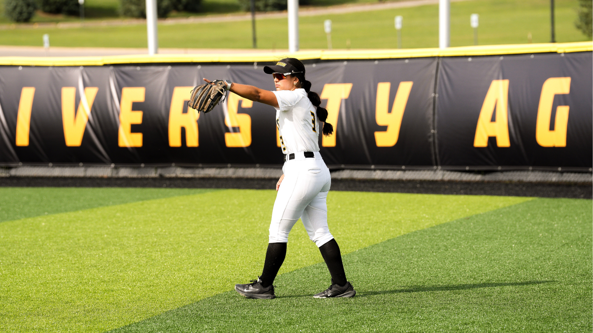 Softball player Chloe Broussard points in the outfield communicating with teammates