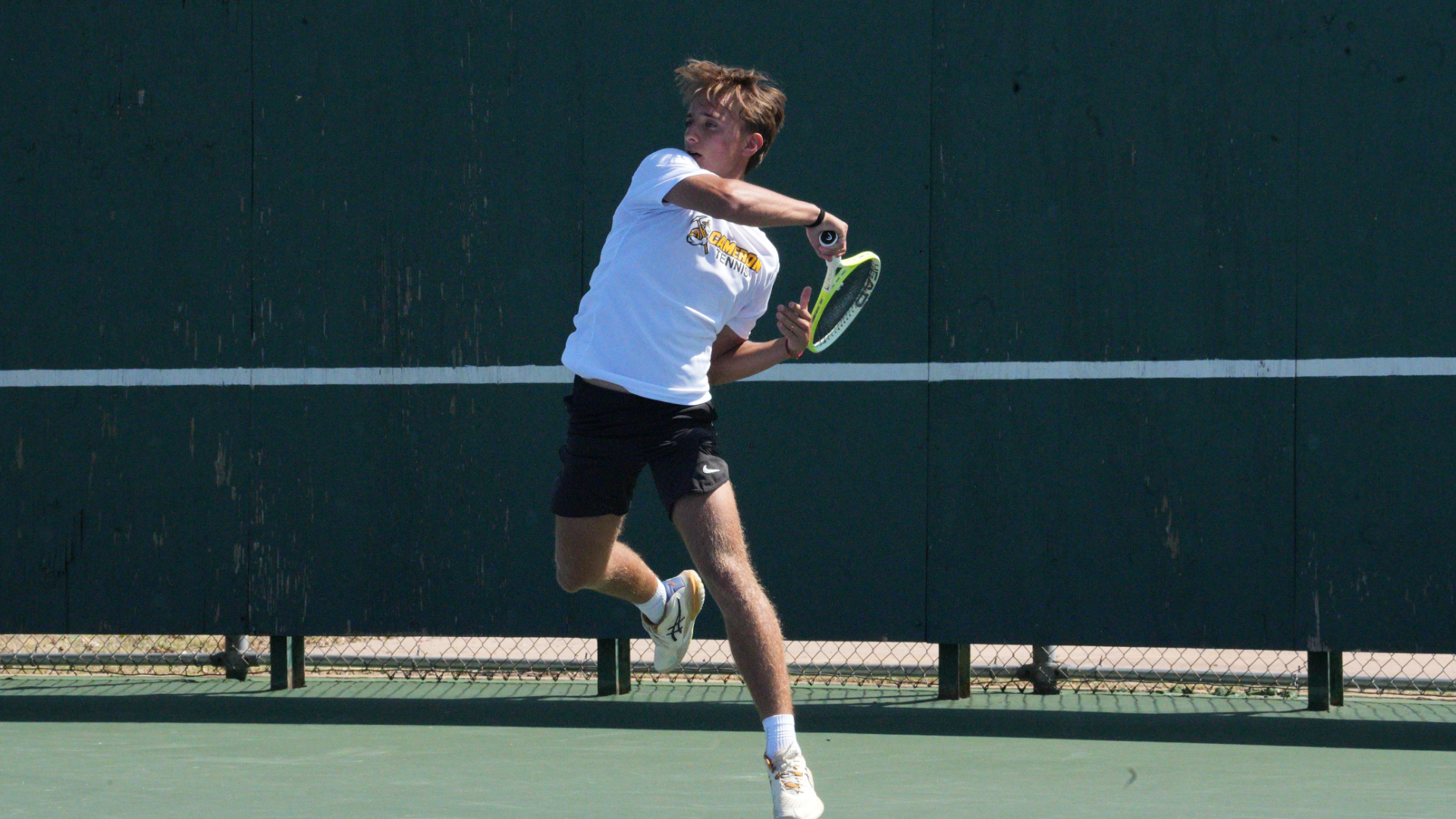 Cameron men's tennis player jumping and hitting a forehand