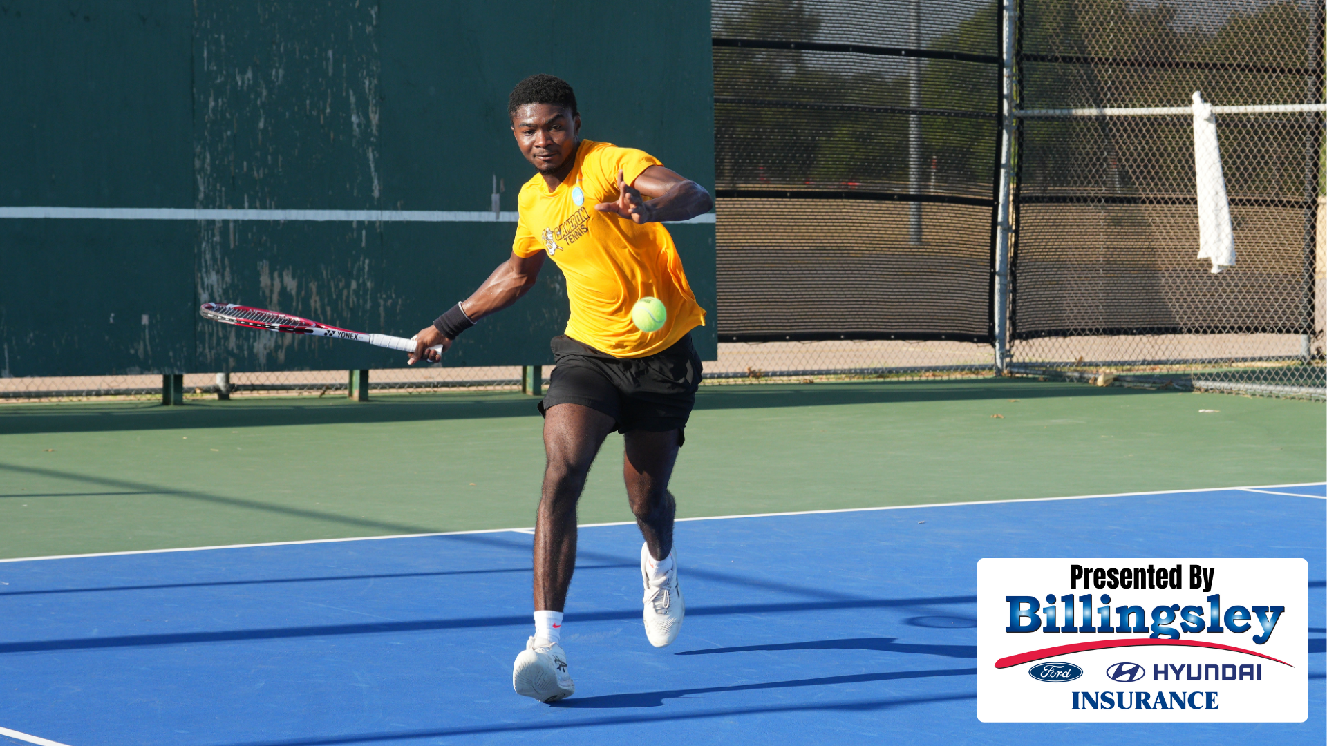 Men's Tennis Player Abubakari Yakubu-Lea hits a forehand including the Presented by Billingsley Family of Dealerships logo