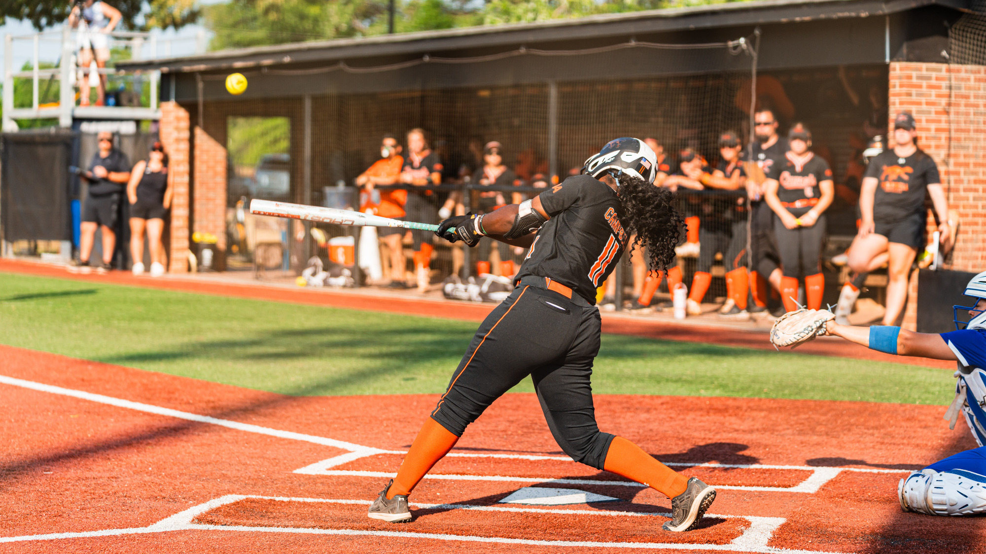 Allyiah Swiney makes contact on a pitch during a game, swinging through the ball at home plate.
