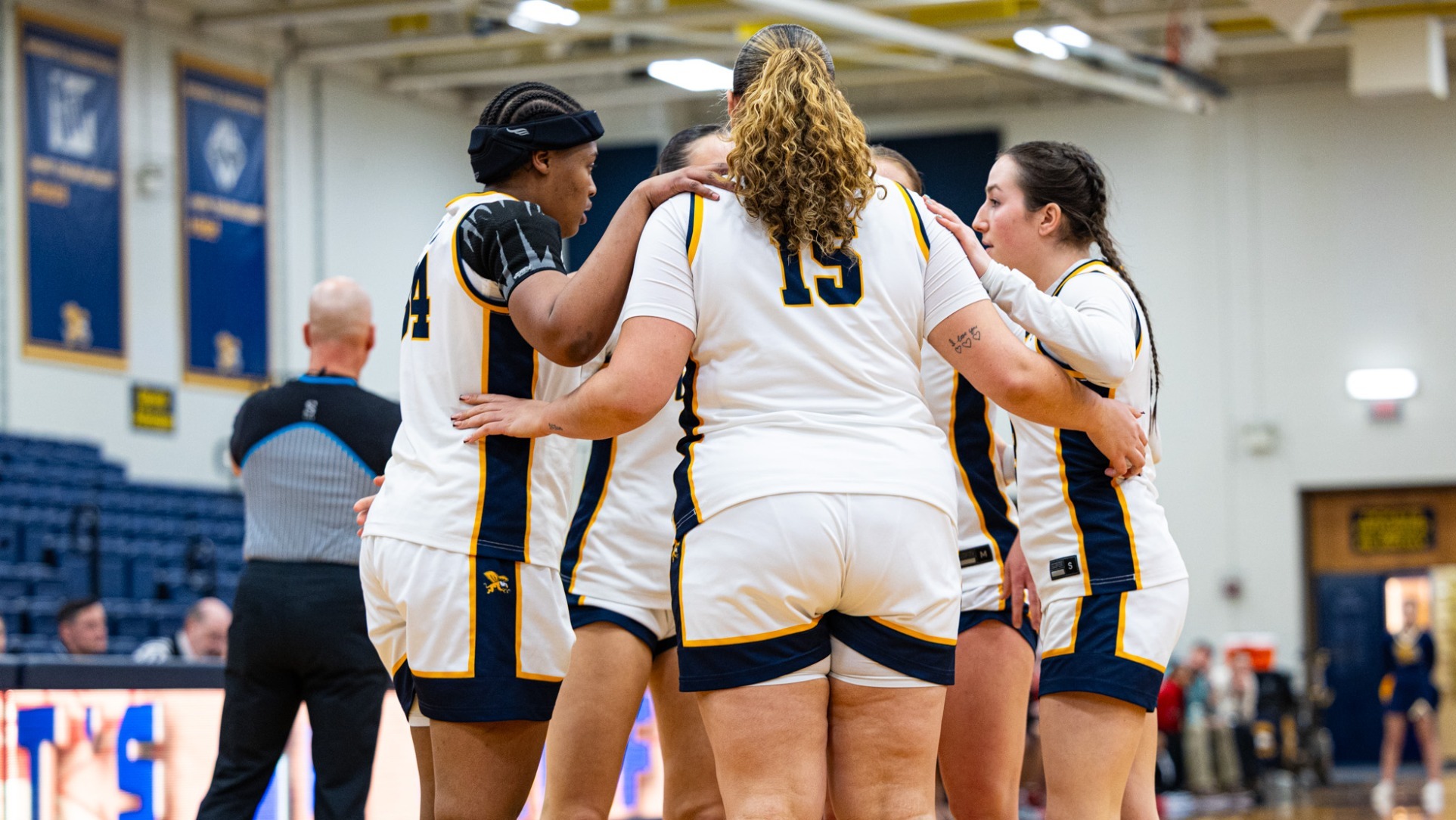 Womens basketball huddles on the court after a foul.