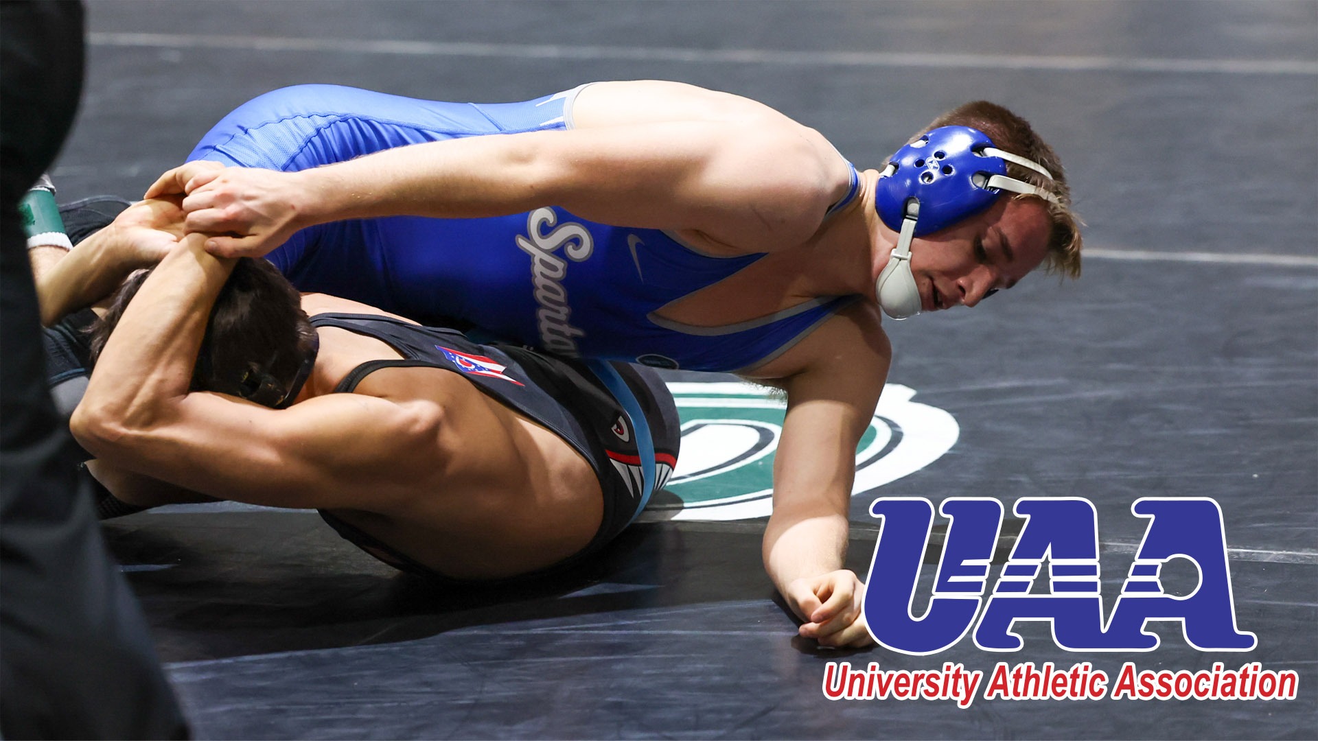 Thomas Wagner wrestling with the UAA logo in the bottom right corner