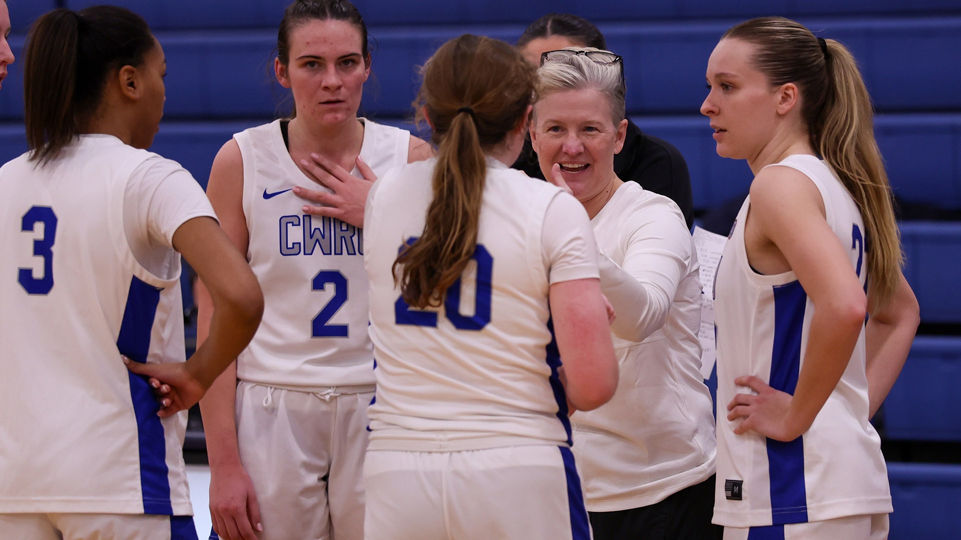 CWRU women's basketball players huddled around Coach Jennifer Reimer