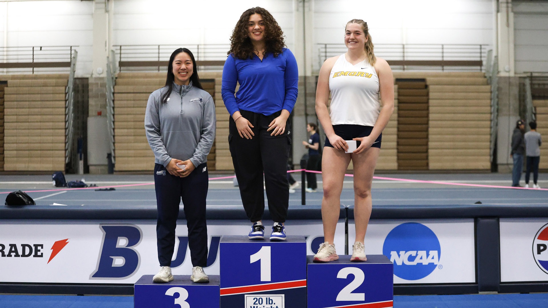 Michelle Lee (center) standing on the podium at the 2026 UAA Indoor Championships