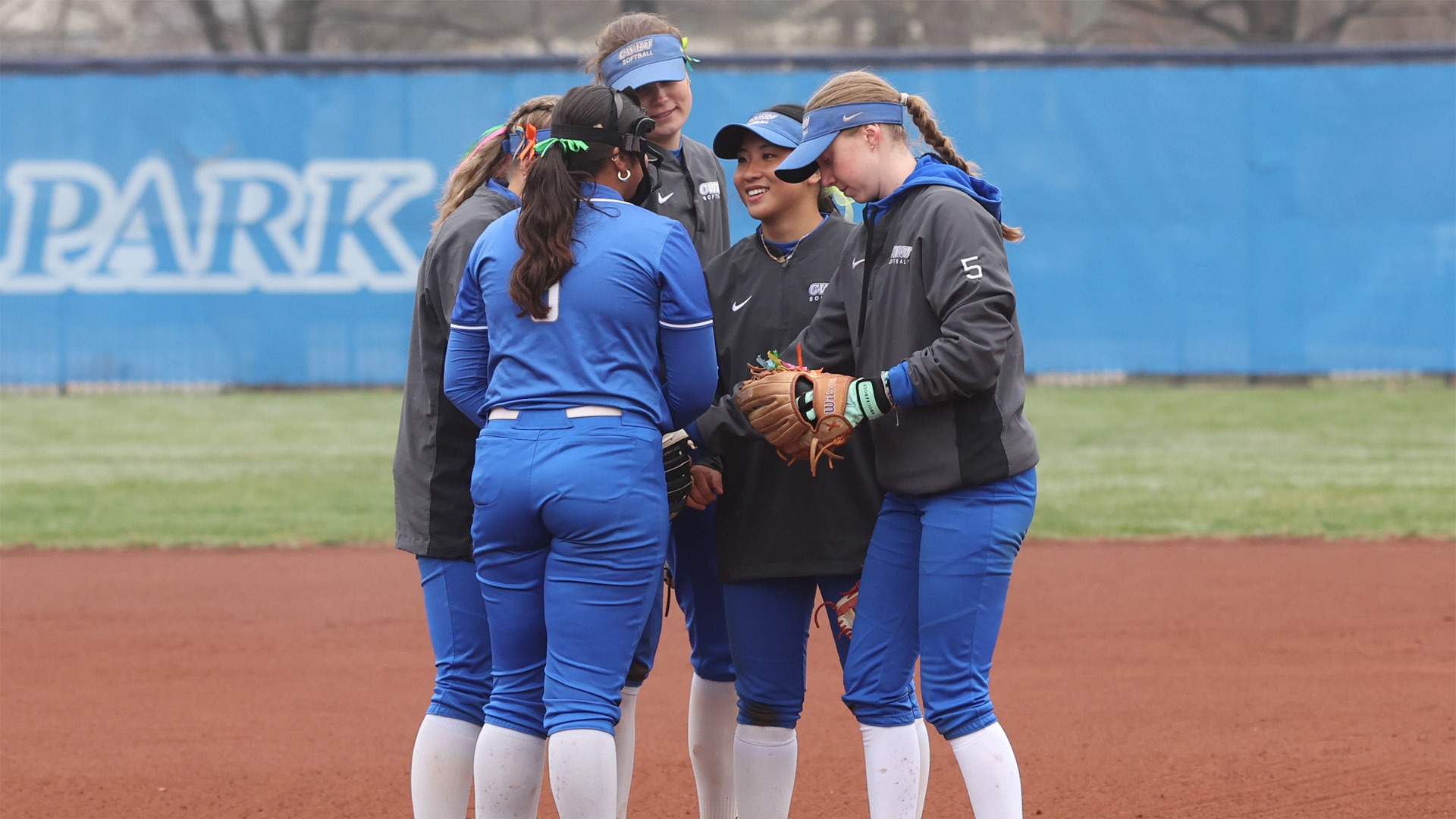 Members of the CWRU Softball infield meeting in a huddle 