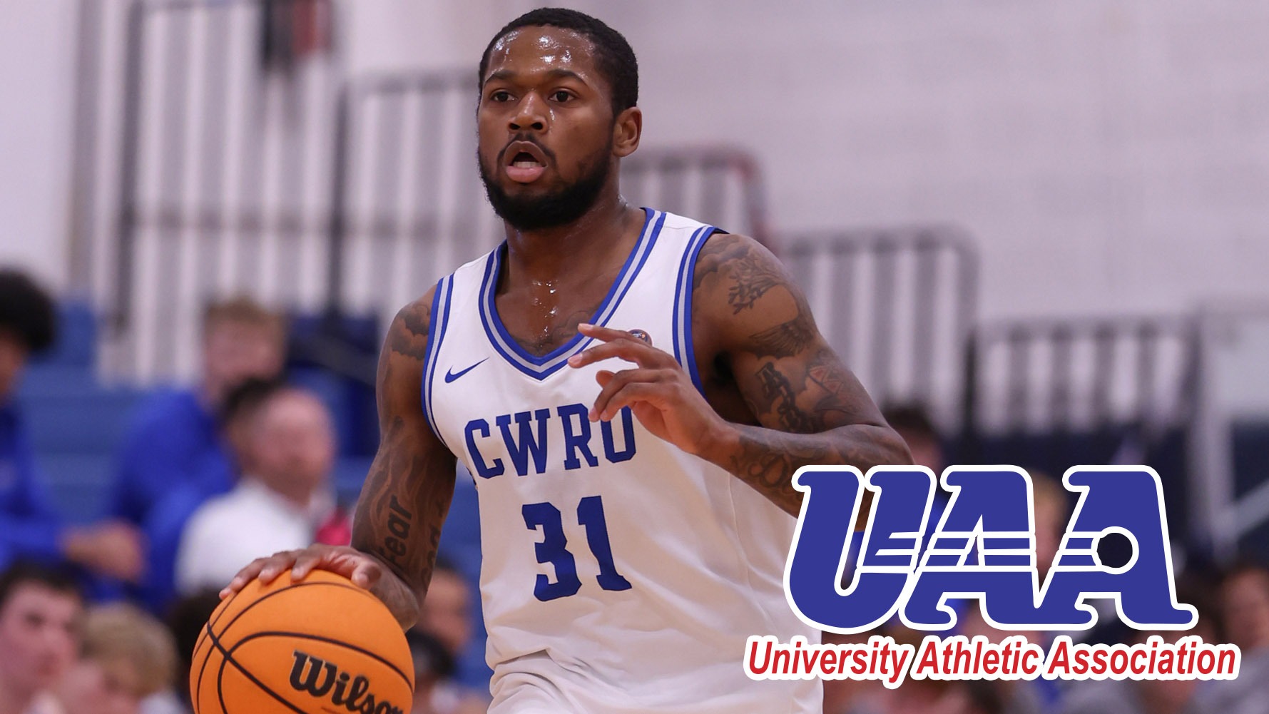Ethan Edwards dribbling with a UAA logo in the corner