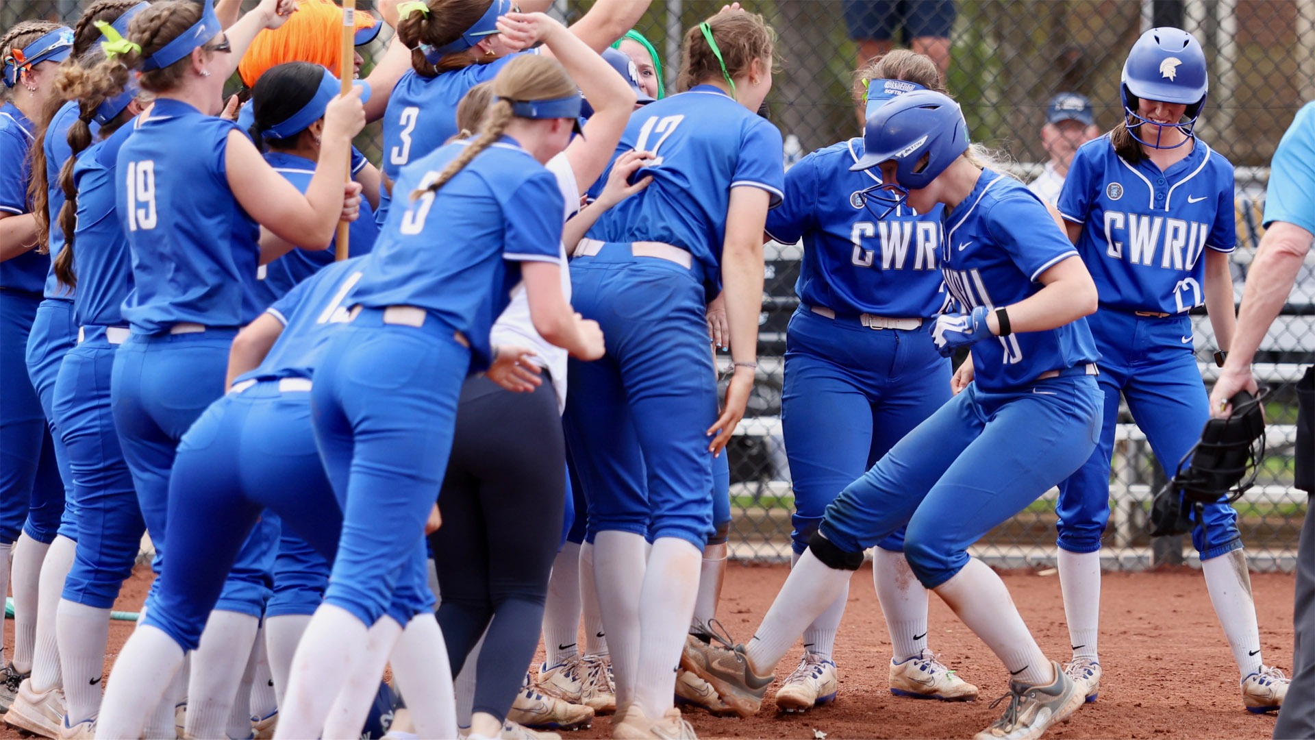 Sophia Becker stepping on home plate surrounded by her teammates after hitting a walk-off home run against Emory
