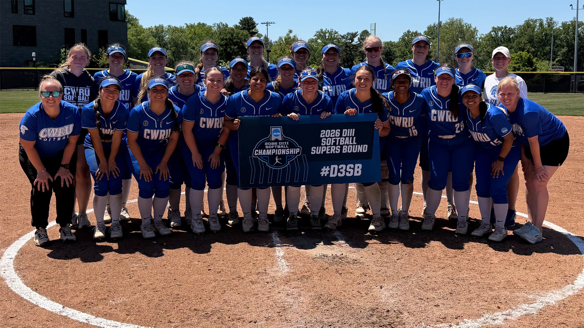 The CWRU Softball team posing with the NCAA Super Regional banner in Swarthmore