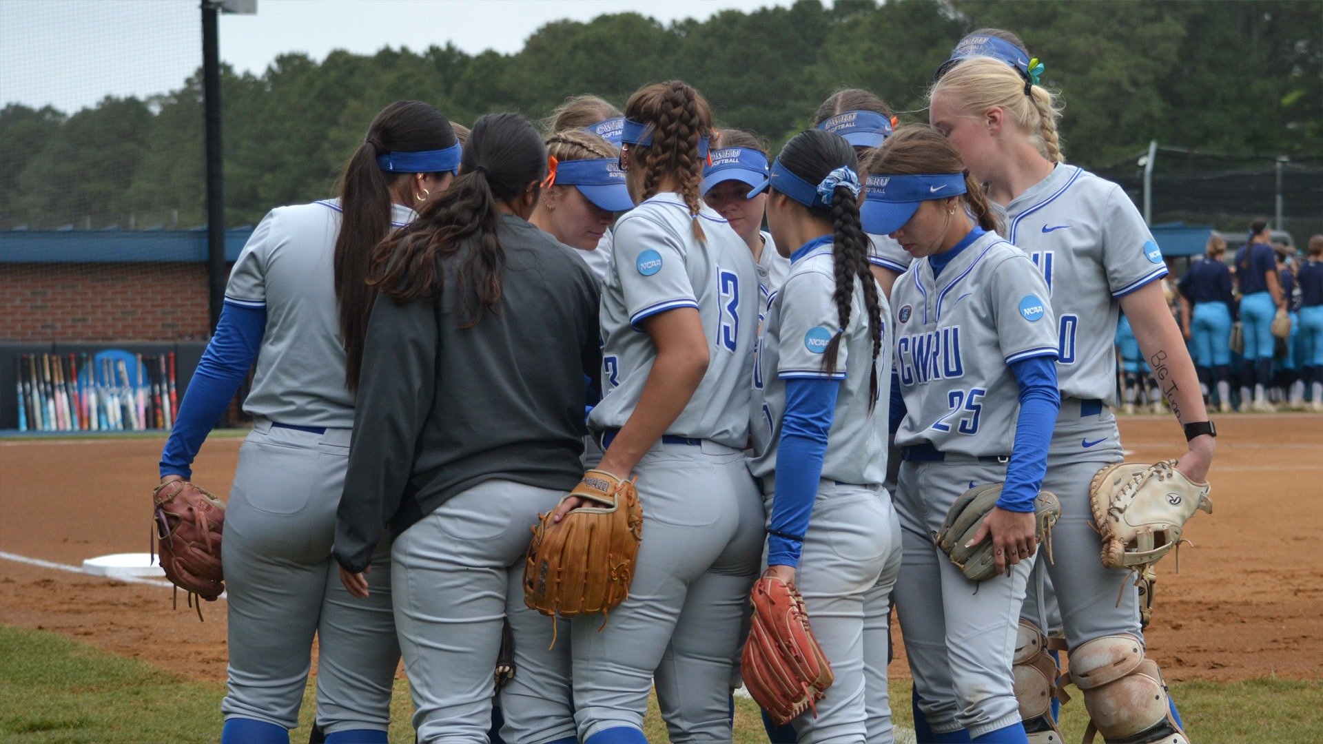 CWRU softball team in a huddle before the second game of the super regional at Virginia Wesleyan