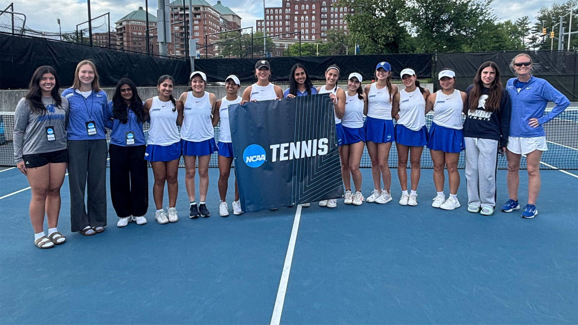 The full CWRU women's tennis team posing with an NCAA Tennis banner in Baltimore