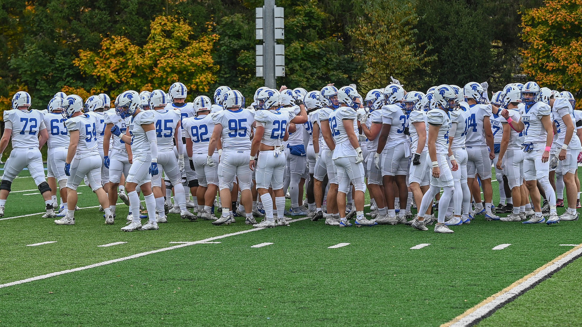 The CWRU football team huddled before its game against Thiel