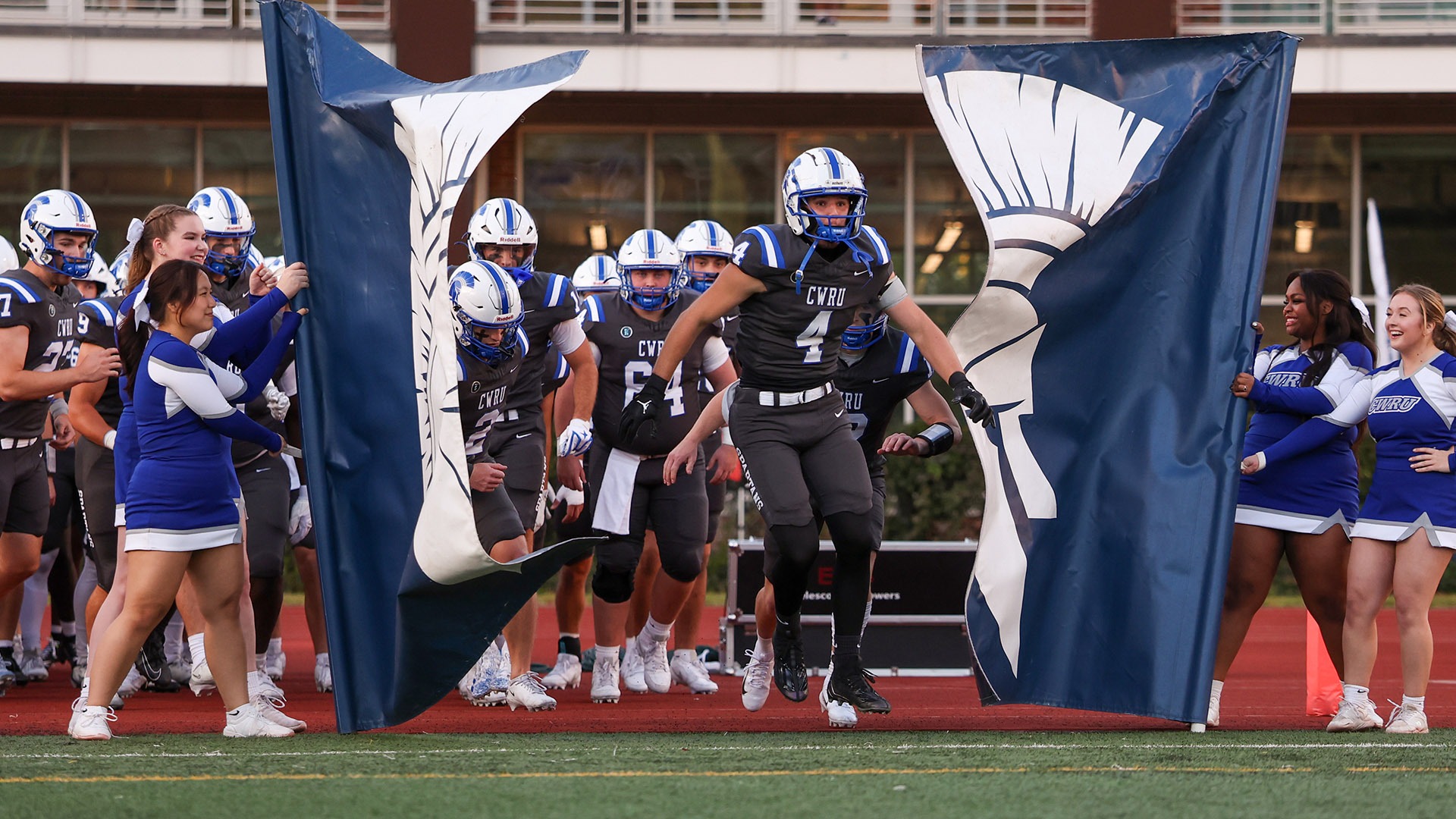 The CWRU football team runs through the banner before its game against Washington & Jefferson