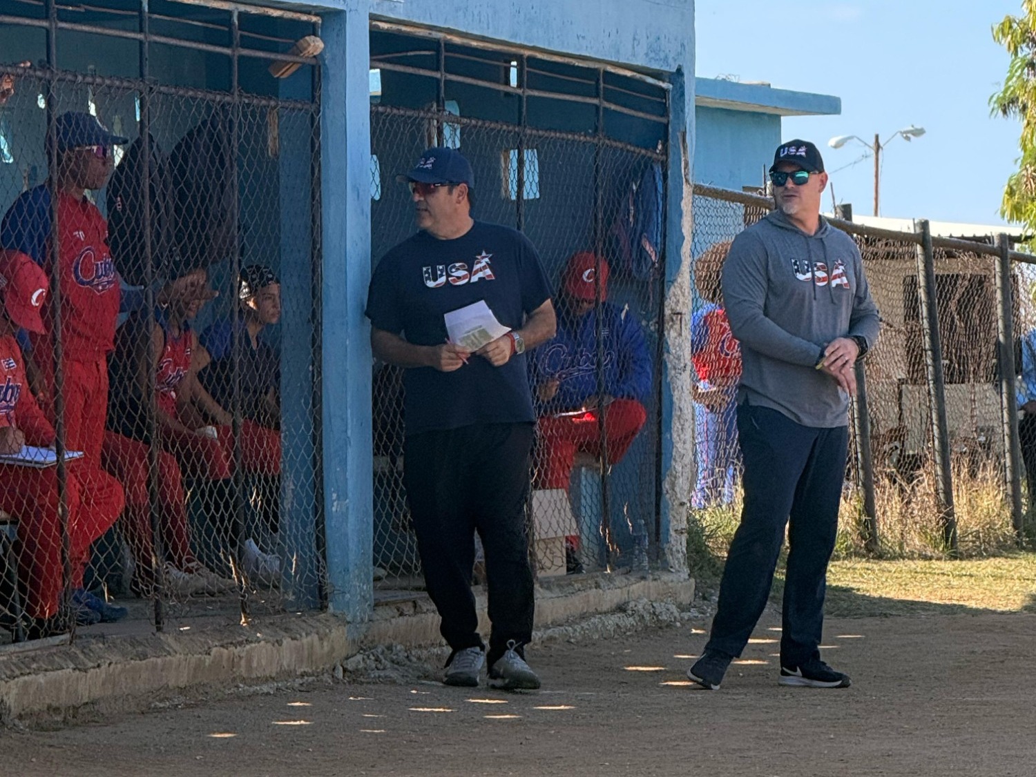 Castleton coaches stand in front of dugout in Canada as part of Team USA