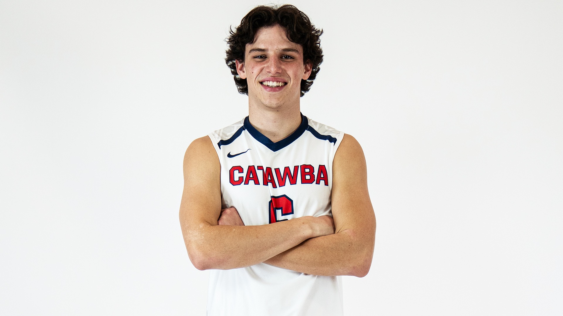 Max Adkisson smiling with crossed arms in Catawba uniform at media day
