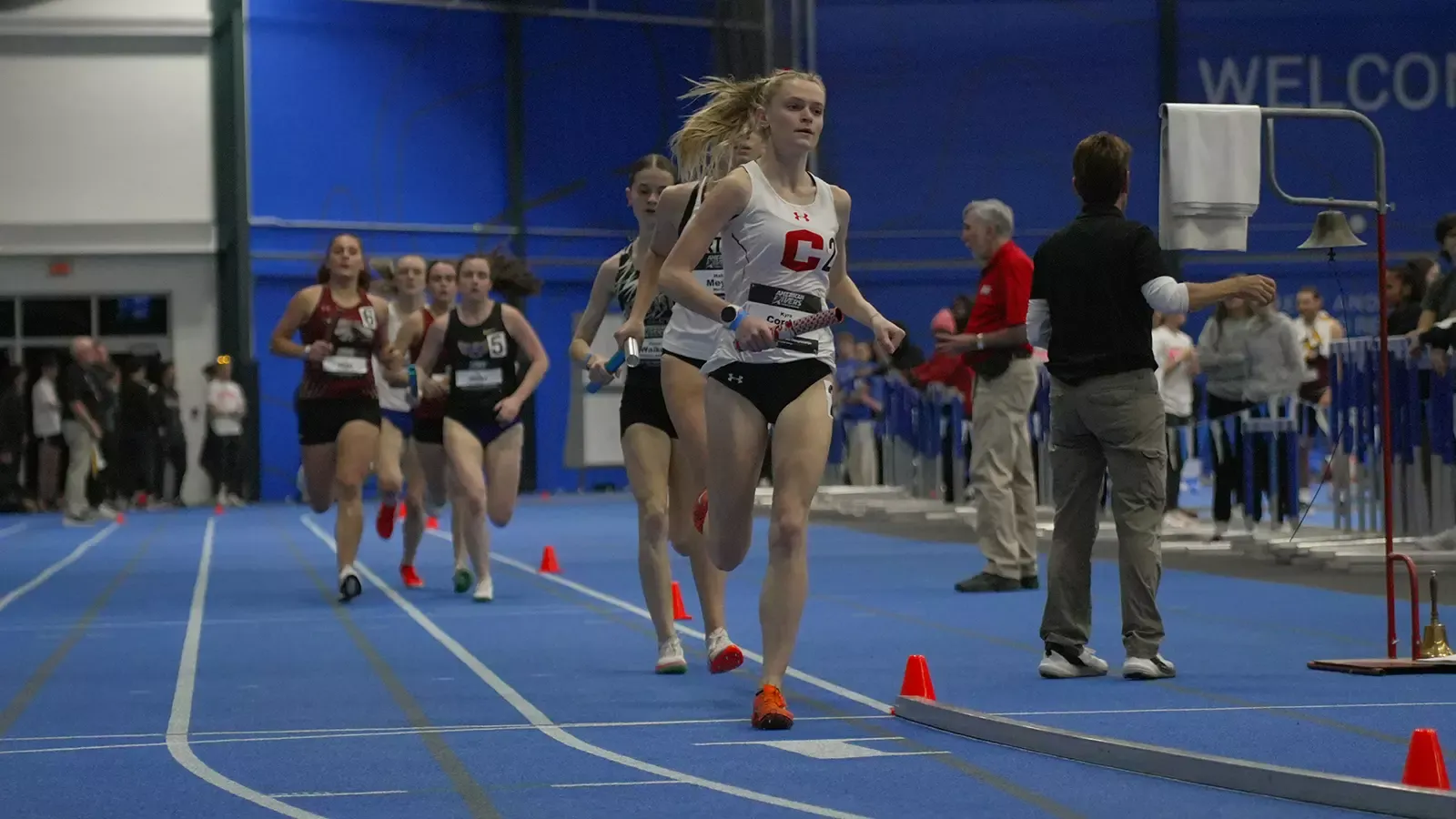 Kyra Cordes running a relay race at conference indoor meet