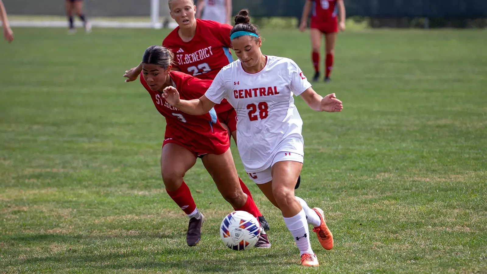Lucy Tiedemann dribbling the ball while being pressured 