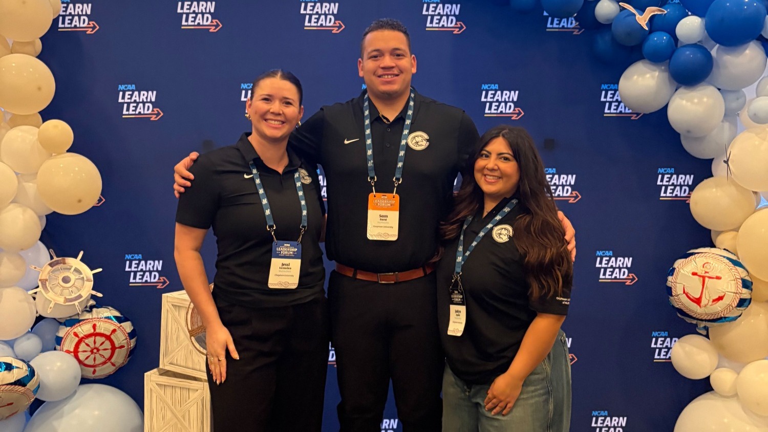 Jessi Lumsden, Sam Forst and Jayden Ayala stand in front of an NCAA backdrop.