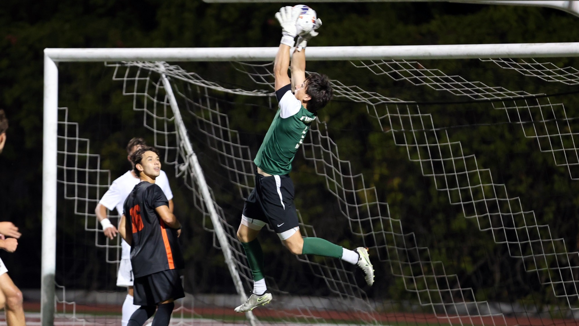 Alex Glynn jumps in the error to make a save on the soccer field.