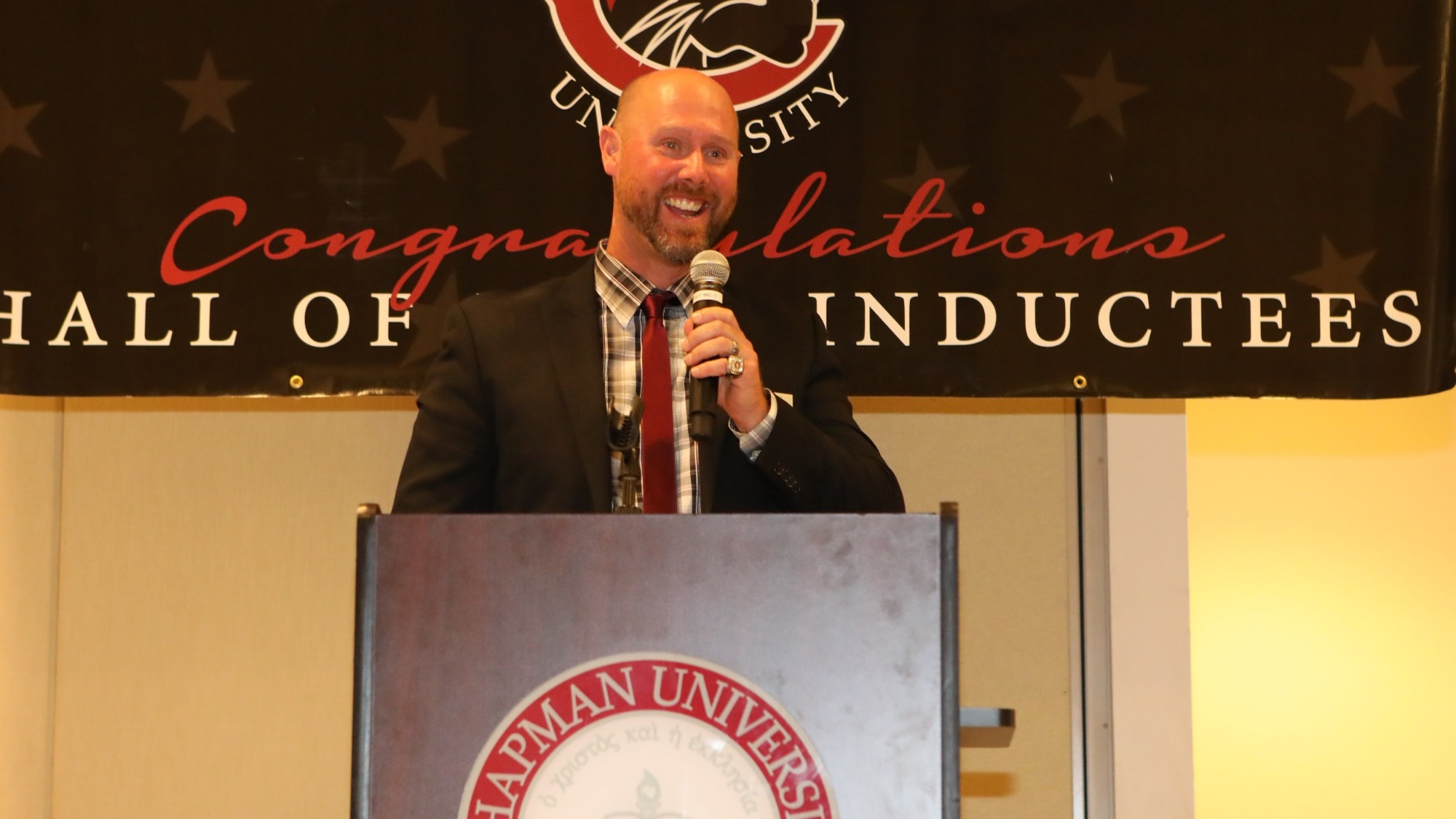 Doug Aiken speaks into a microphone on stage.