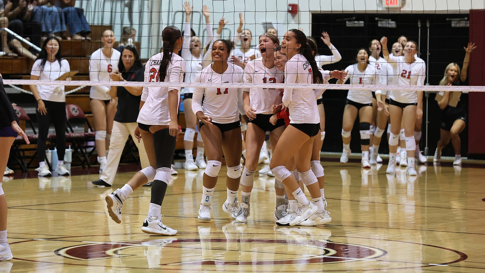 Volleyball players huddle on the court to celebrate scoring a point.