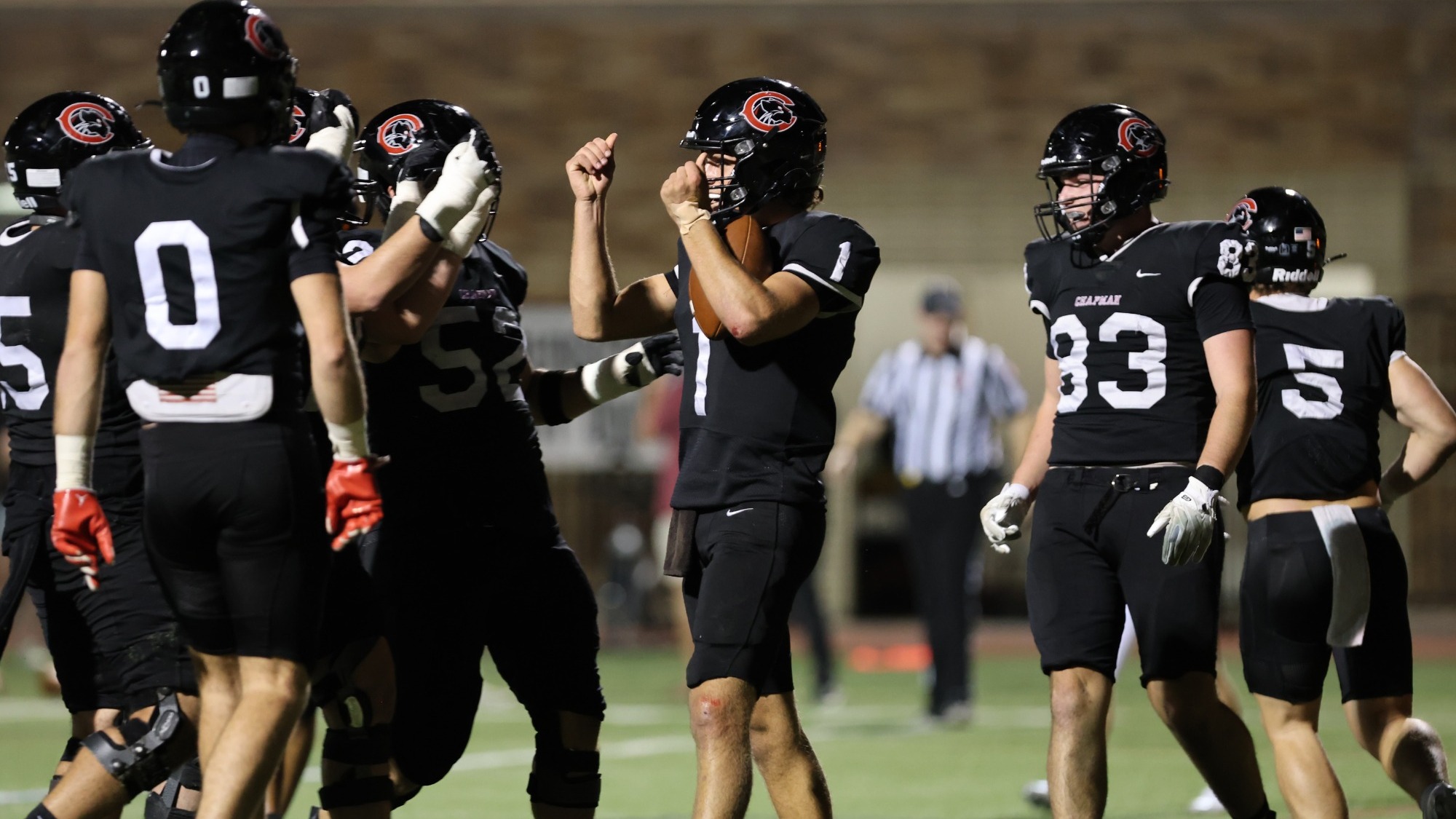 Eli Brandt celebrates on the football field with teammates after scoring a touchdown.